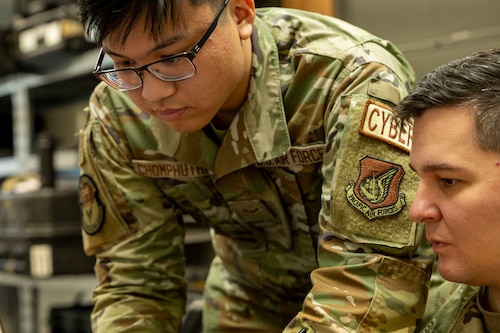 Service members work on computer.
