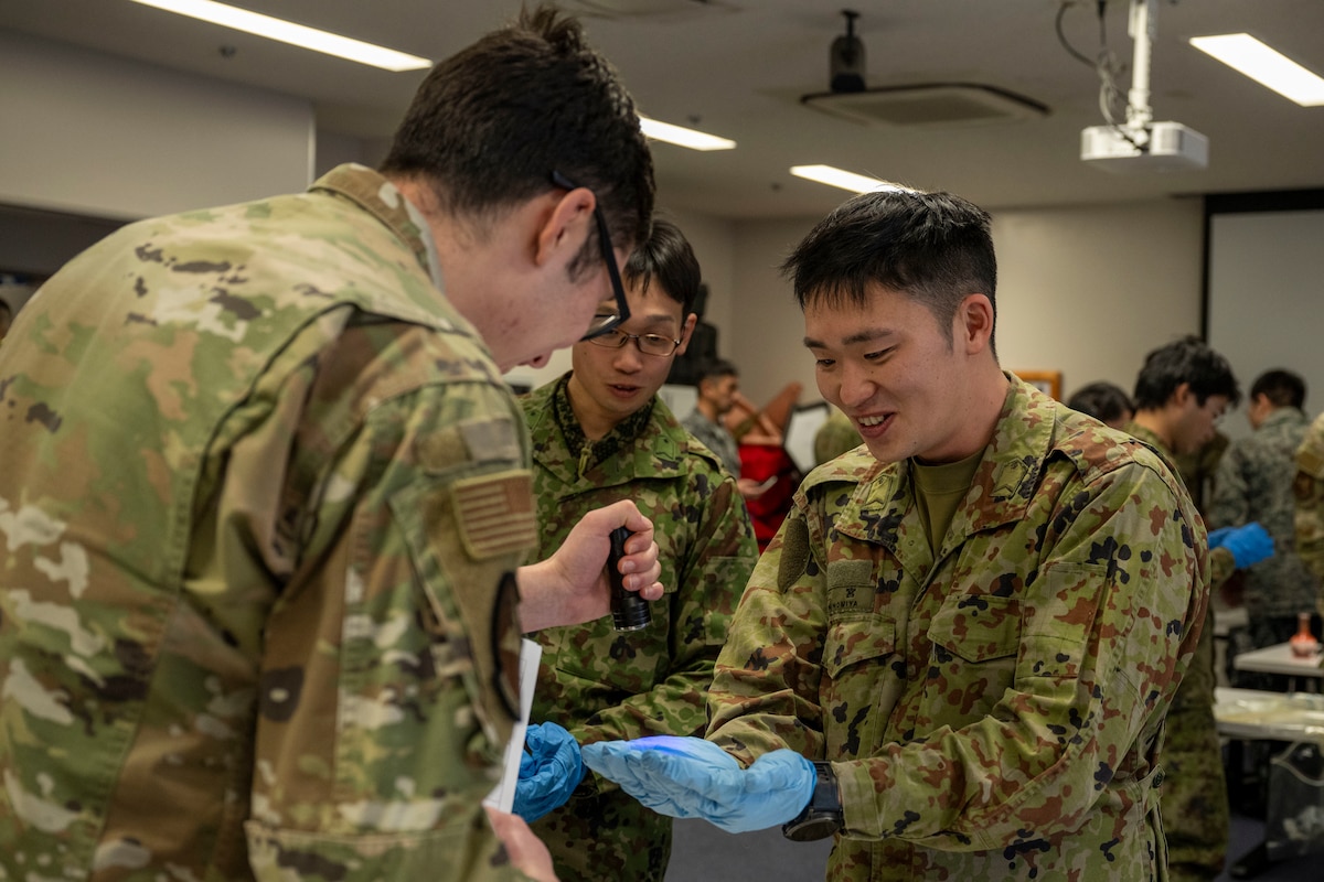 U.S. Air Force Airman 1st Class Tristian Worley, left, 35th Civil Engineering Squadron emergency manager, examines a participant’s gloves for residue during a bilateral chemical, biological, radiological and nuclear (CBRN) training.