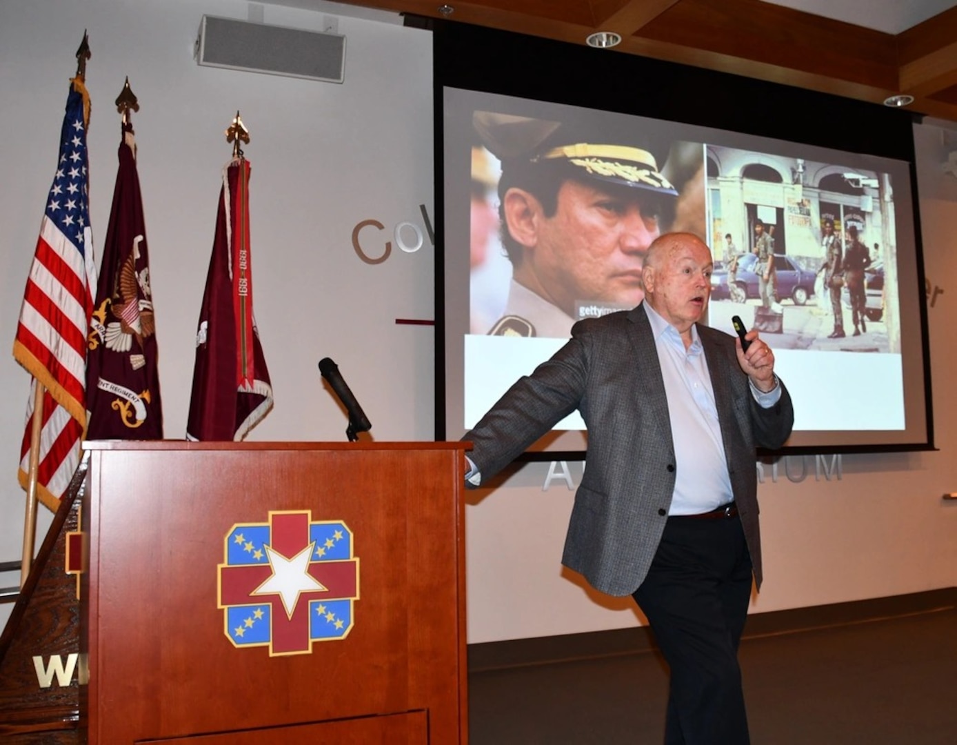 Kurt Muse, a former prisoner of dictator Manuel Noriega, speaks about his ordeal to Soldiers and civilian personnel at the Weaver Auditorium in Womack Army Medical Center on Friday, January 31, 2025. A slide of dictator is seen on the screen behind Muse.