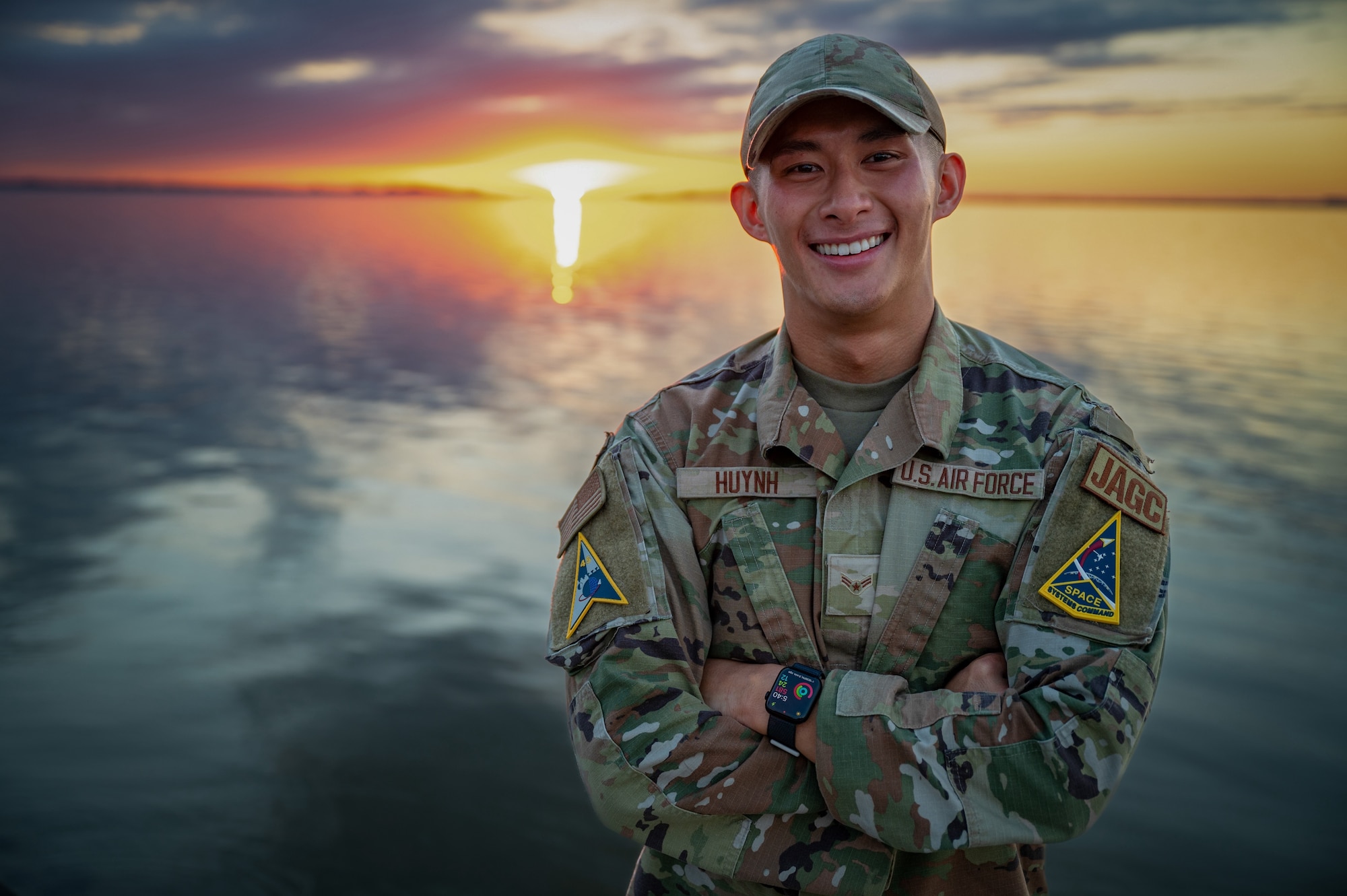 An Airman poses for a picture in front of a sunset.