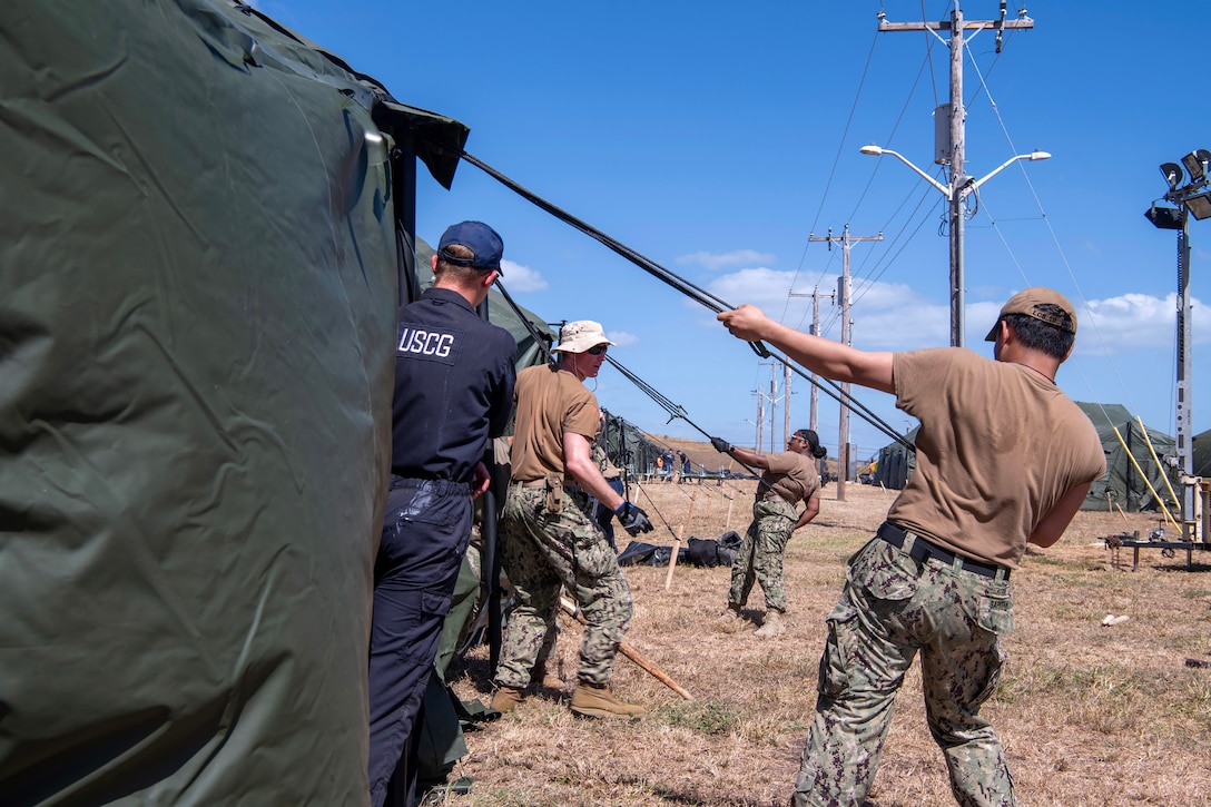 Sailors assigned to Freedom-variant littoral combat ship USS St. Louis (LCS 19) and Coast Guardsmen assigned to Coast Guard Cutter Resolute erect expeditionary shelter tents in support of the Naval Station Guantanamo Bay’s Migrant Operations Center expansion February 2, 2025, as part of Operation Southern Guard. At the direction of the President of the United States to the Department of Homeland Security (DHS) and the Department of Defense, U.S. military service members are supporting removal operations led by DHS at Naval Station Guantanamo Bay.