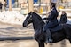 A soldier is sitting on a black horse with icy streets in the distance.