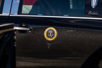 The presidential seal is seen on the side of a black vehicle.