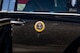 The presidential seal is seen on the side of a black vehicle.