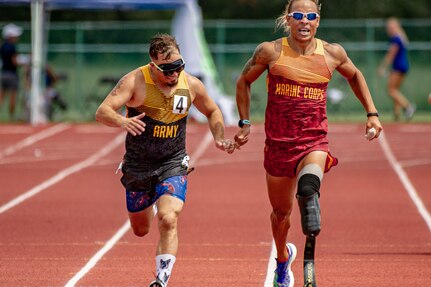 Retired U.S. Army Staff Sgt. Michael Murphy, left, is guided by U.S. Marine Sgt. Peter Keating while competing in a track event during the 2022 Department of Defense Warrior Games