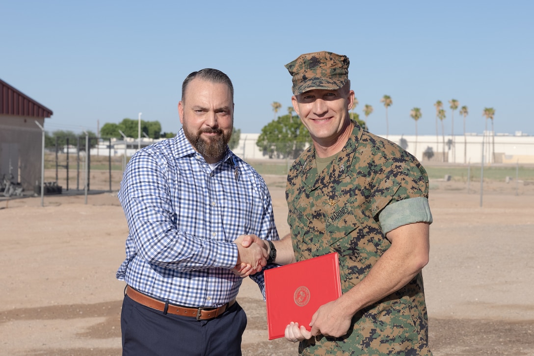 U.S. Marine Corps Col. Jared K. Stone, right, commanding officer, Marine Corps Air Station (MCAS) Yuma, and retired U.S. Marine Corps Master Sgt. Matthew Danque, training and standardization officer, MCAS Yuma air traffic control, pose for a photo after Danque received the Meritorious Civilian Service Award (MCSA) at MCAS Yuma, Arizona, Aug. 15, 2024. Danque received the MCSA for everything he had accomplished with the El Centro expansion project. (U.S. Marine Corps photo by Lance Cpl. Elizabeth Gallagher)