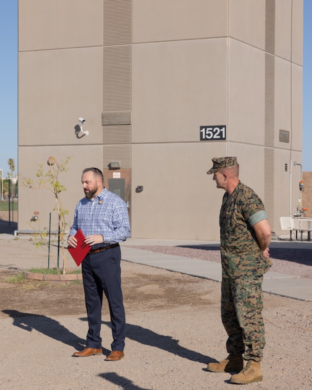 U.S. Marine Corps Col. Jared K. Stone, right, commanding officer, Marine Corps Air Station (MCAS) Yuma, listens to retired U.S. Marine Corps Master Sgt. Matthew Danque, training and standardization officer, MCAS Yuma air traffic control, speak after receiving the Meritorious Civilian Service Award (MCSA) at MCAS Yuma, Arizona, Aug. 15, 2024. Danque received the MCSA for everything he had accomplished with the El Centro expansion project. (U.S. Marine Corps photo by Lance Cpl. Elizabeth Gallagher)