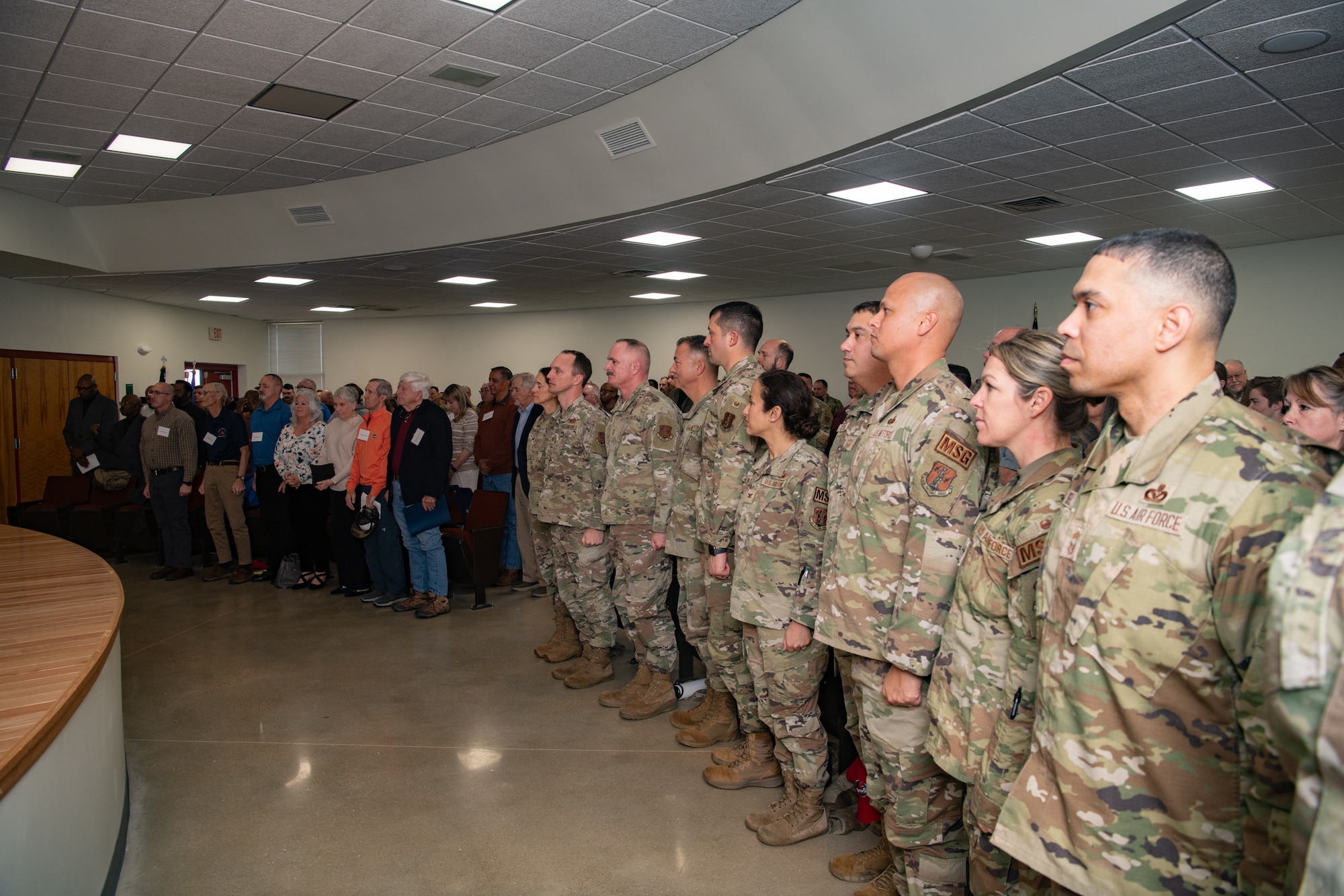 Military and civilian members standing in the audience