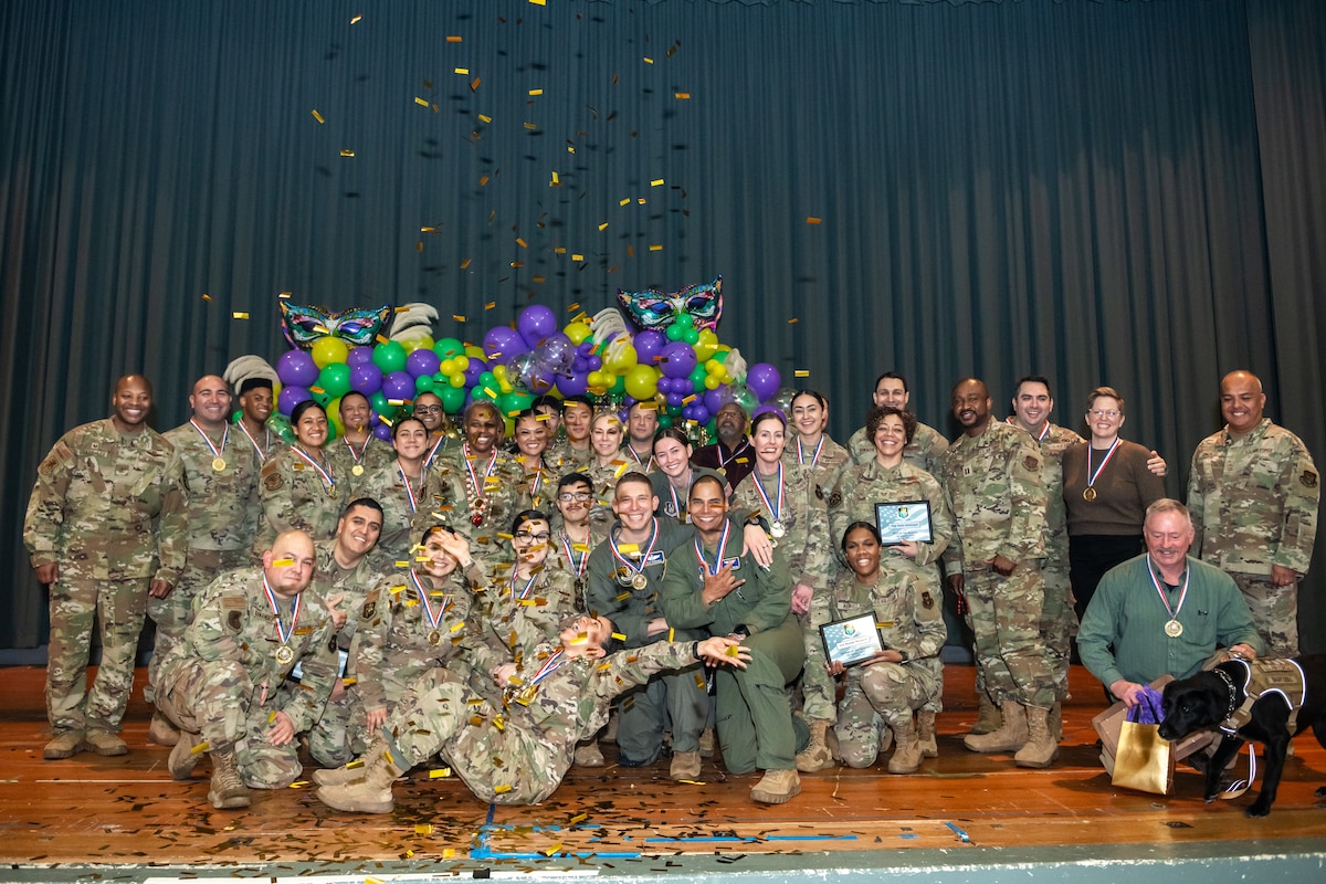 A large group photo of military and civilian members celebrating on stage.