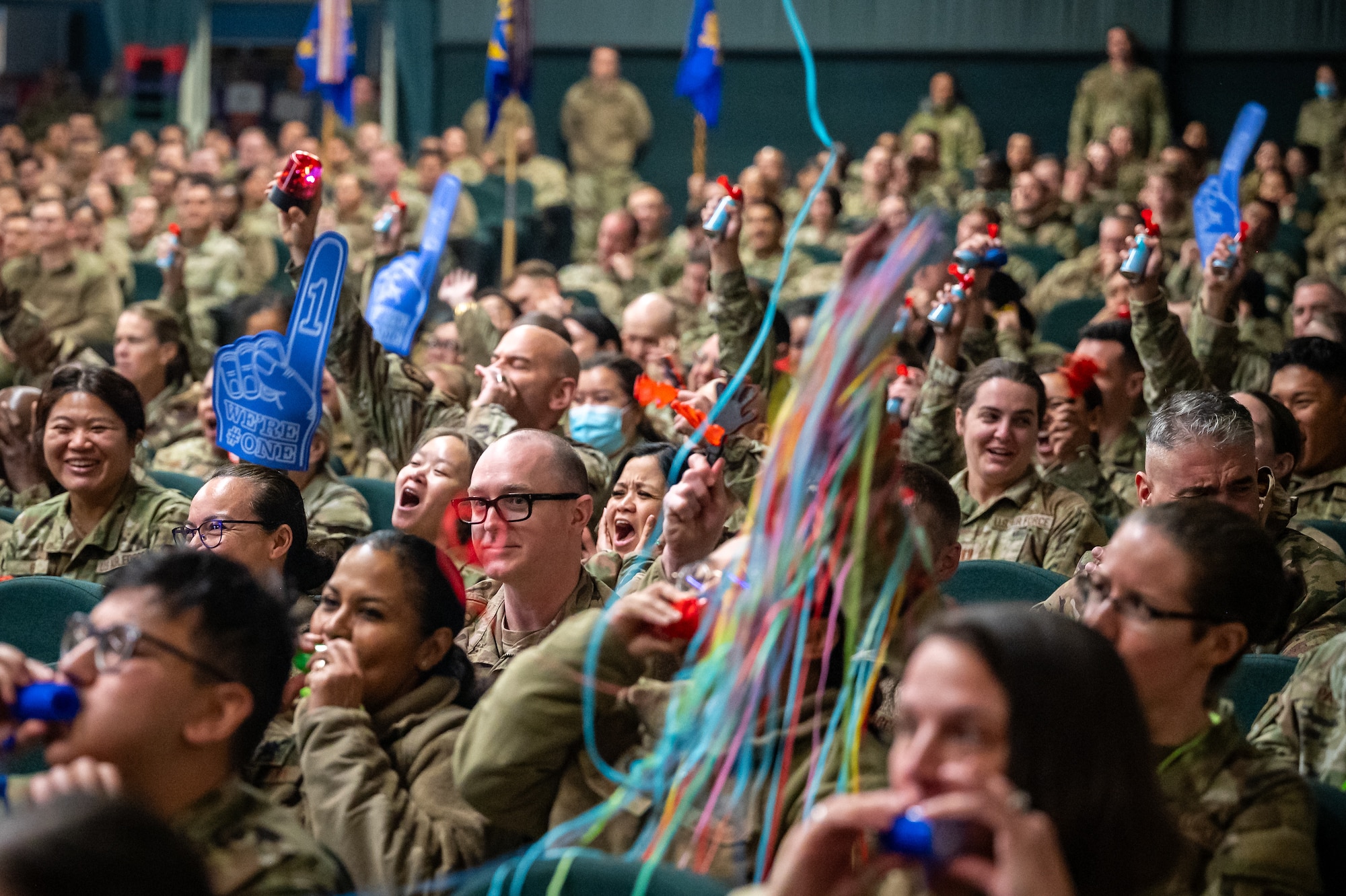 A group of military members celebrate by making noise and throwing streamers.