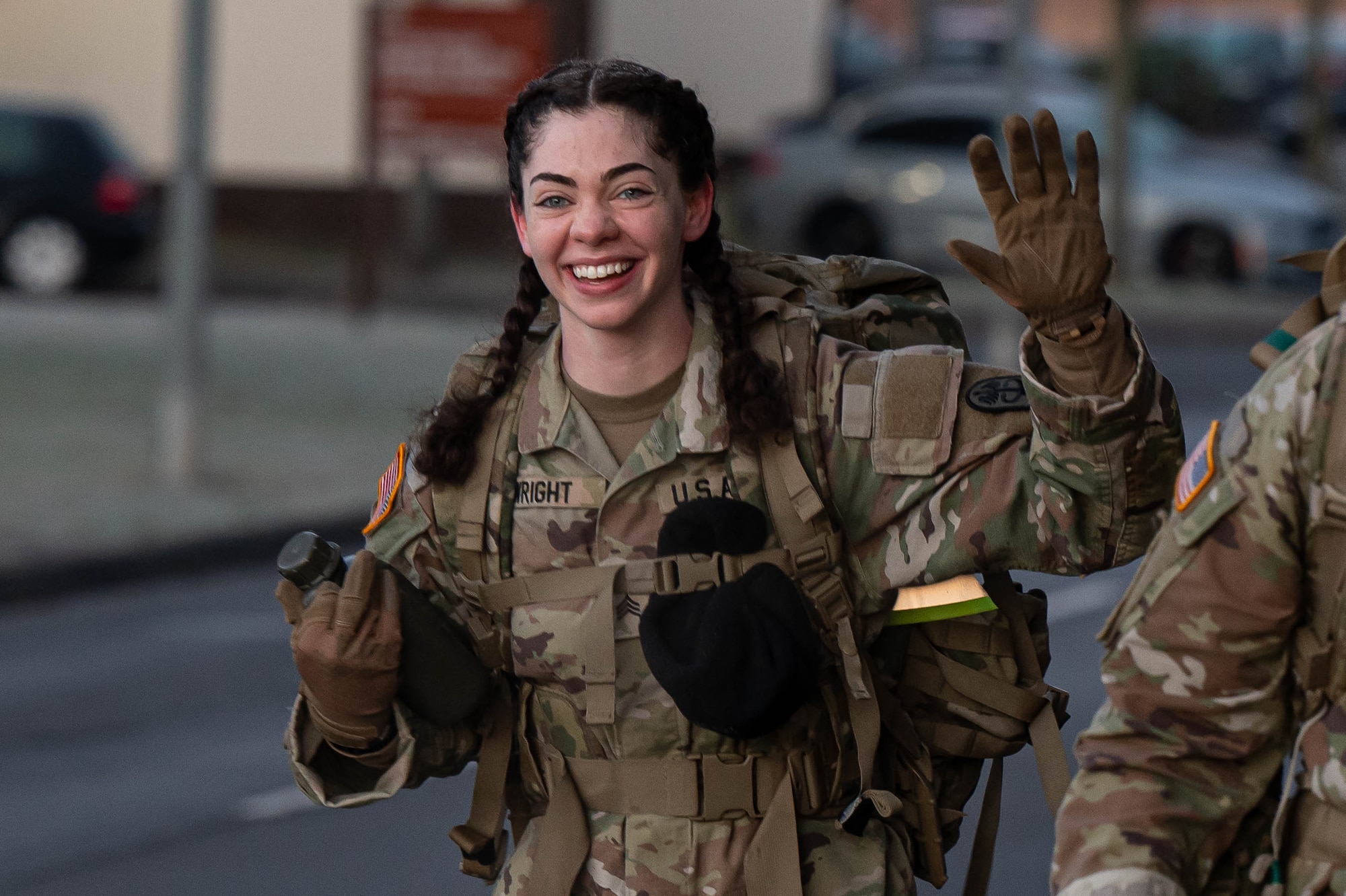 A soldier waves during a ruck march.
