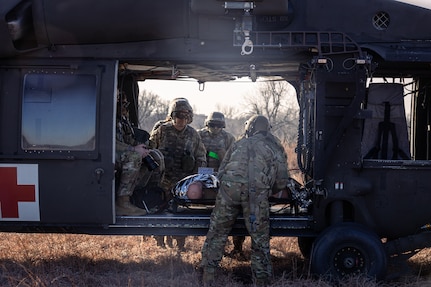 Crew chiefs assigned to Charlie Company, 1st Battalion, 169th Aviation Regiment, Oklahoma Army National Guard, and Airmen assigned to the 72nd Air Base Wing, Tinker Air Force Base, secure medical evacuation (MEDEVAC) dummies into a UH-60 Black Hawk during a joint training exercise at the Glenwood Training Area in Oklahoma City, Jan. 28, 2025. During the exercise, combat medics from the 72nd Air Base Wing, Tinker Air Force Base, practiced patient stabilization, MEDEVAC calls, and loading procedures while coordinating closely with the OKARNG pilots conducting helicopter insertions in austere environments. (Oklahoma National Guard photo by Spc. Danielle Rayon)