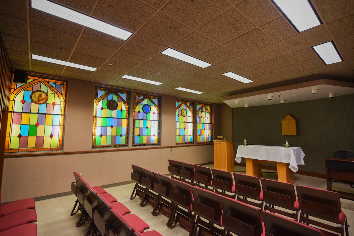 A set of chairs facing a podium beside a wall lined with stained glass at the medical center