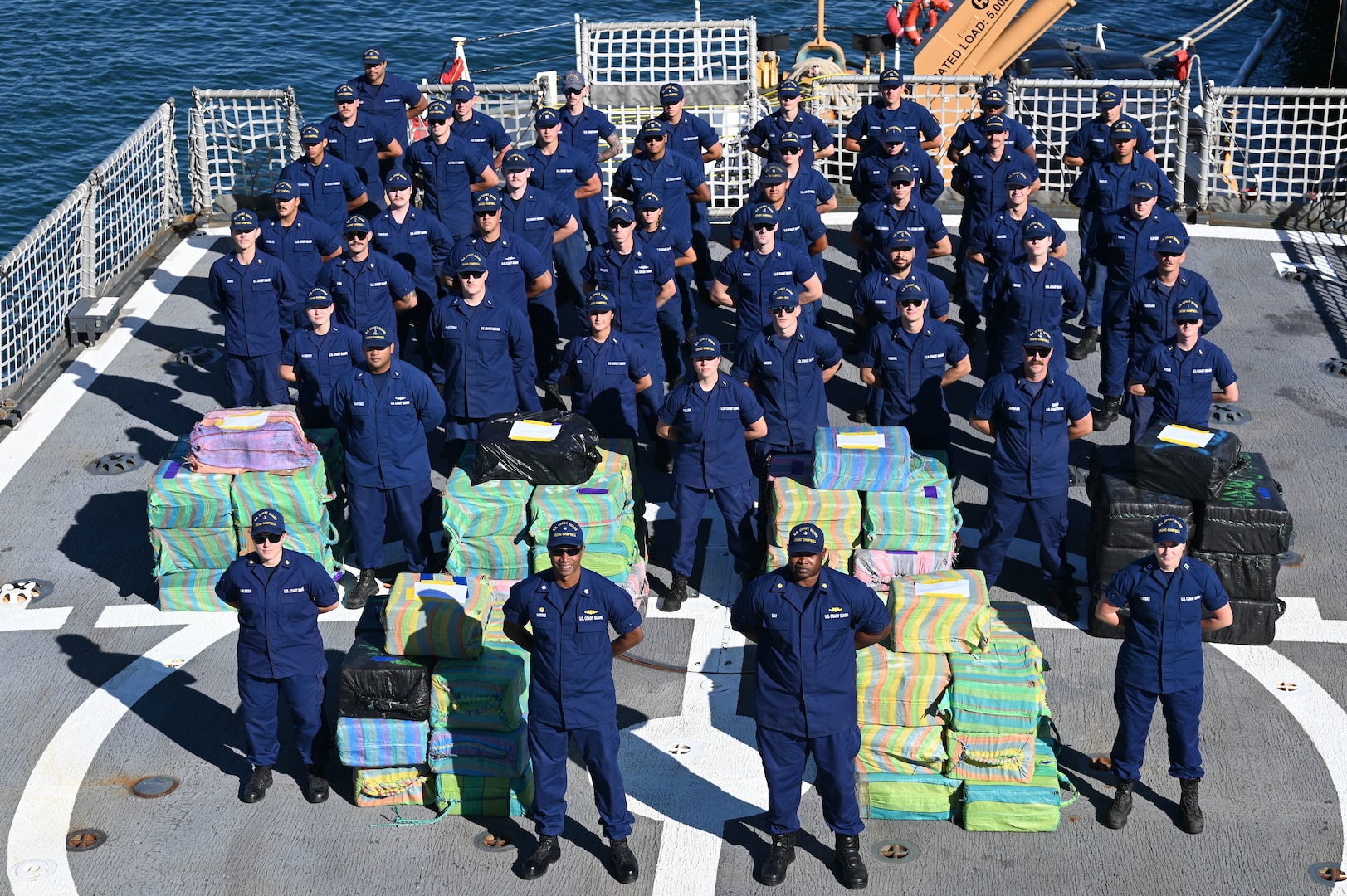 The crew of USCGC Campbell (WMEC 909) stands for a photo accompanied by more than 8,000 pounds of cocaine worth an assessed street value of approximately $91.3 million in Port Everglades, Florida, Jan. 27, 2025. The Campbell crew offloaded the illegal drugs from two interdictions in the international waters of the Eastern Pacific Ocean. (U.S. Coast Guard photo by Petty Officer 1st Class Diana Sherbs)