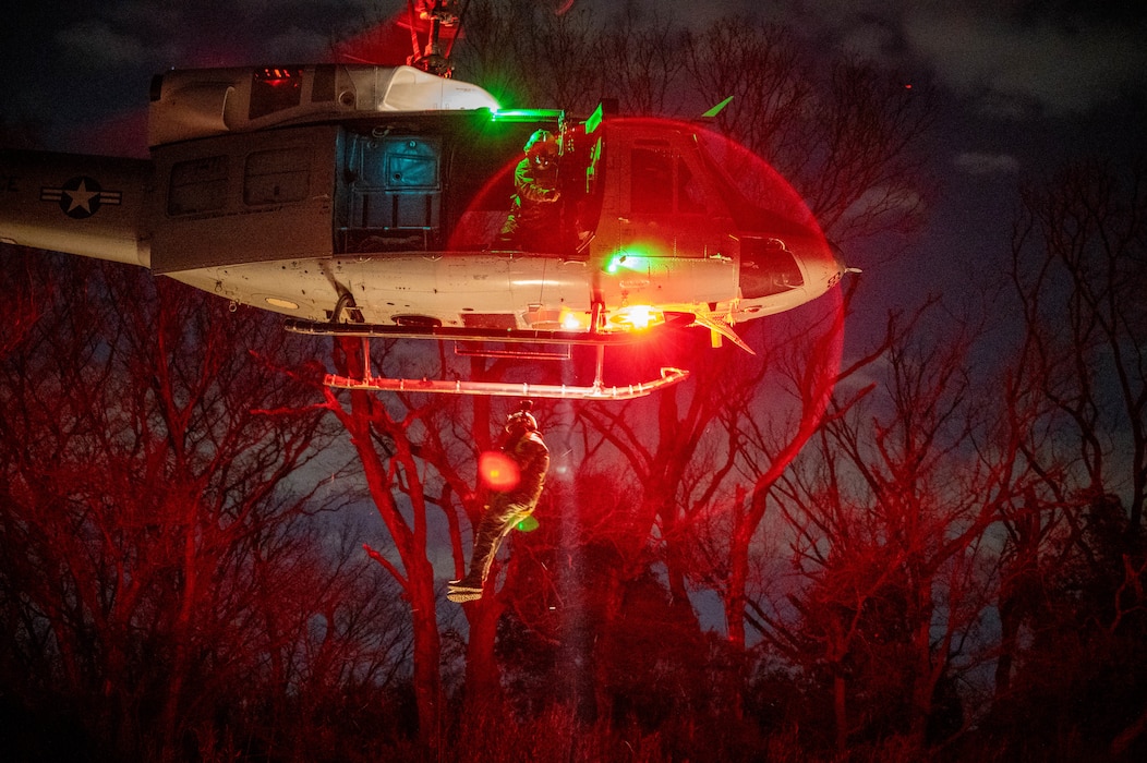 U.S. Air Force Tech. Sgt. Jeovany Vasquez, 459th Airlift Squadron UH-1N Huey instructor flight engineer, conducts a simulated rescue operation during a search and rescue hoist training maneuver Jan. 28, 2025.