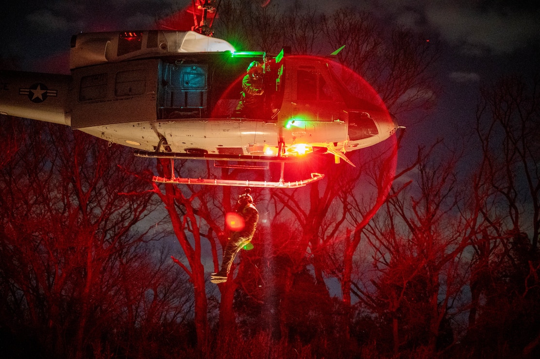 U.S. Air Force Tech. Sgt. Jeovany Vasquez, 459th Airlift Squadron UH-1N Huey instructor flight engineer, conducts a simulated rescue operation during a search and rescue hoist training maneuver Jan. 28, 2025.