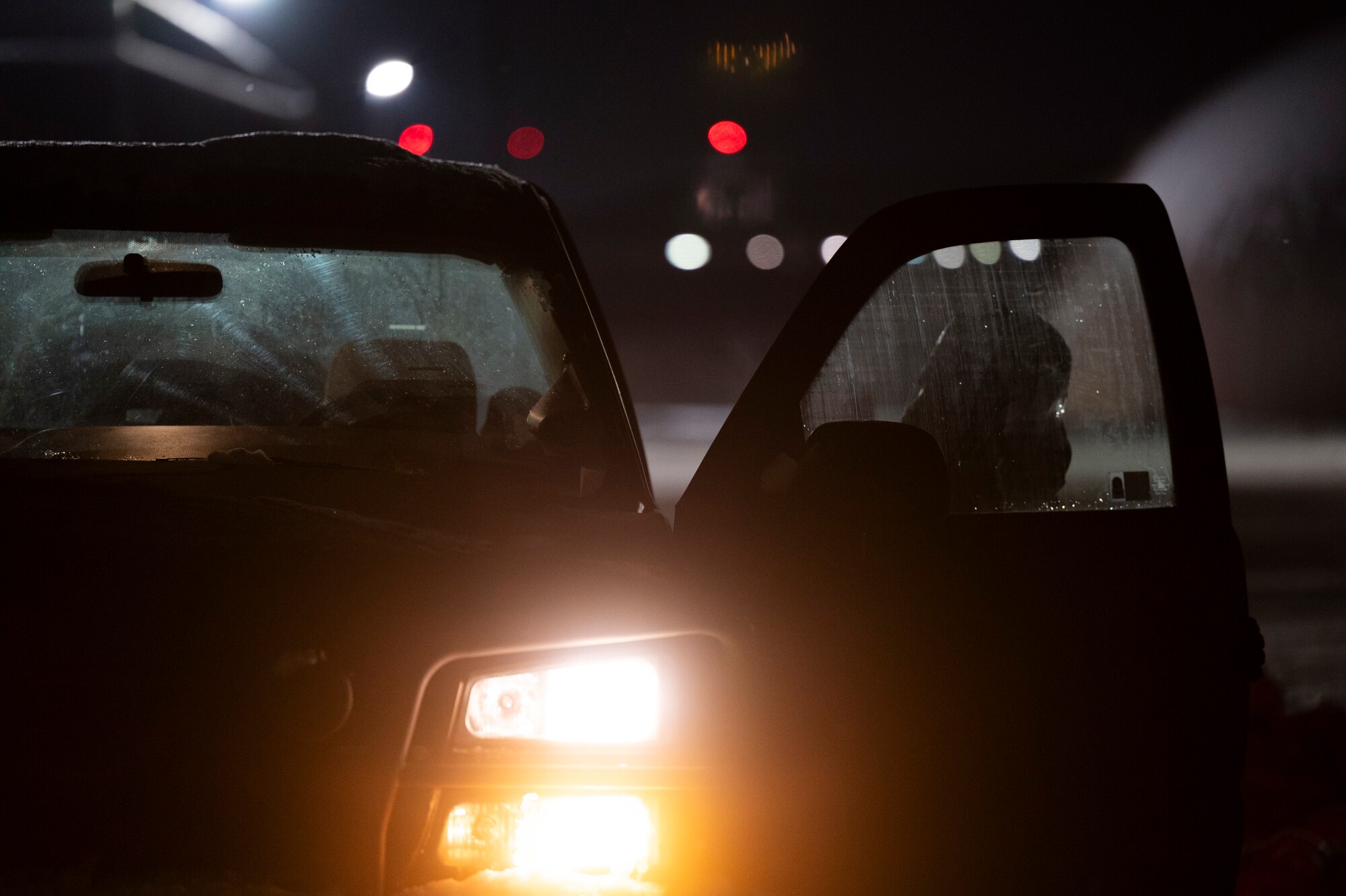An Airman in protective gear exits a truck at night.