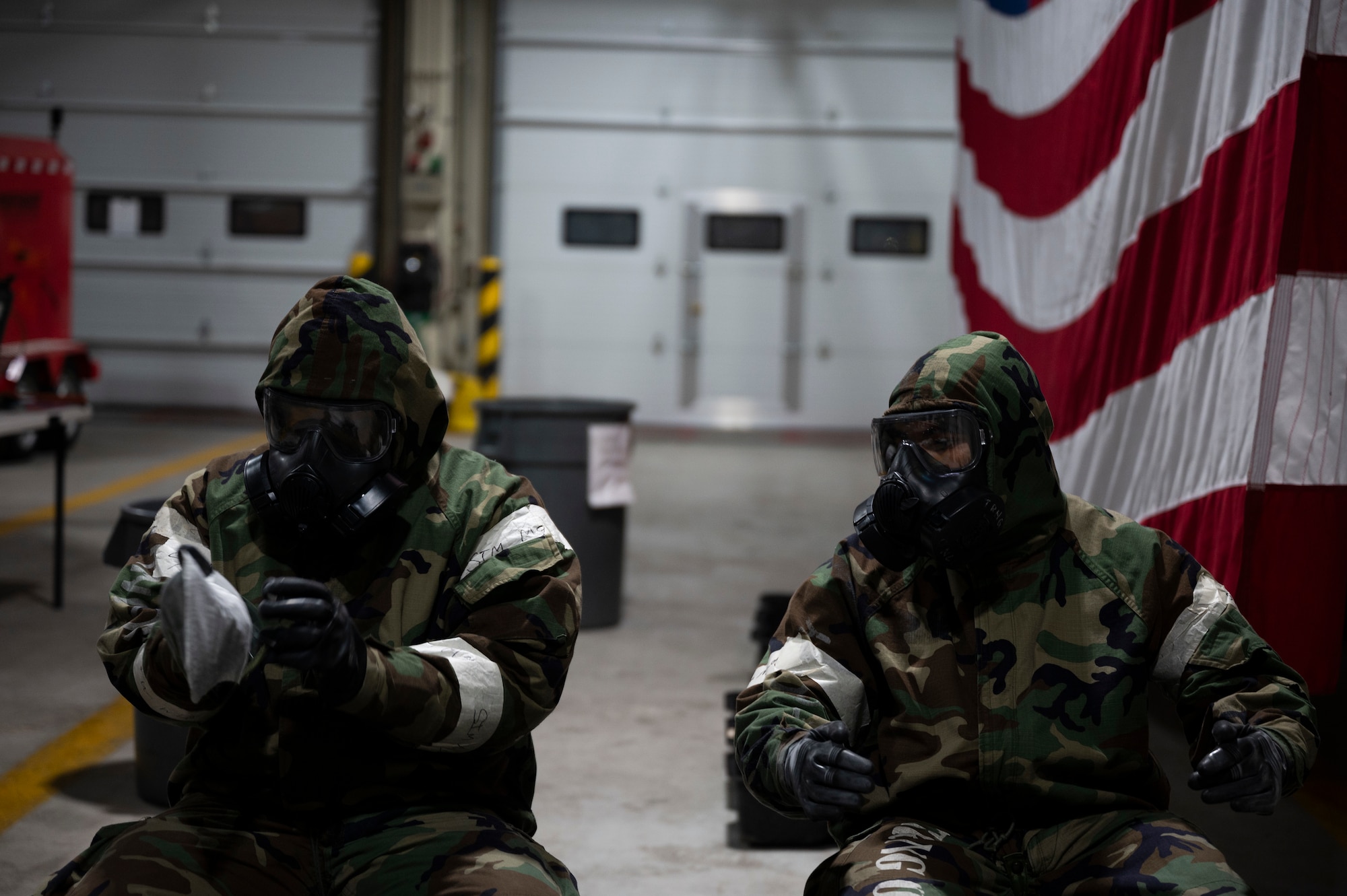 Two Airmen in protective gear use decontamination procedures.