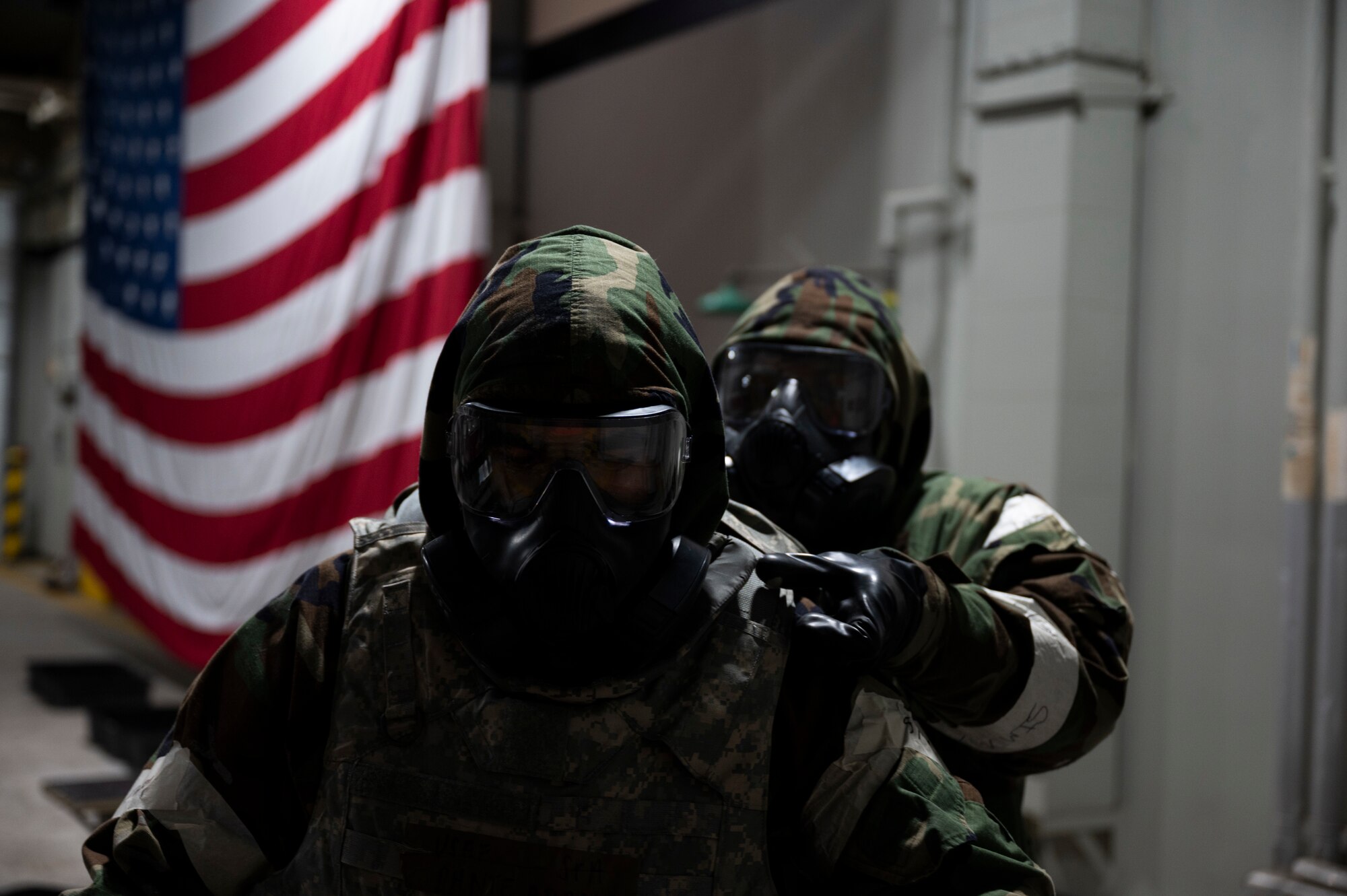 Two Airmen in protective gear use decontamination procedures.