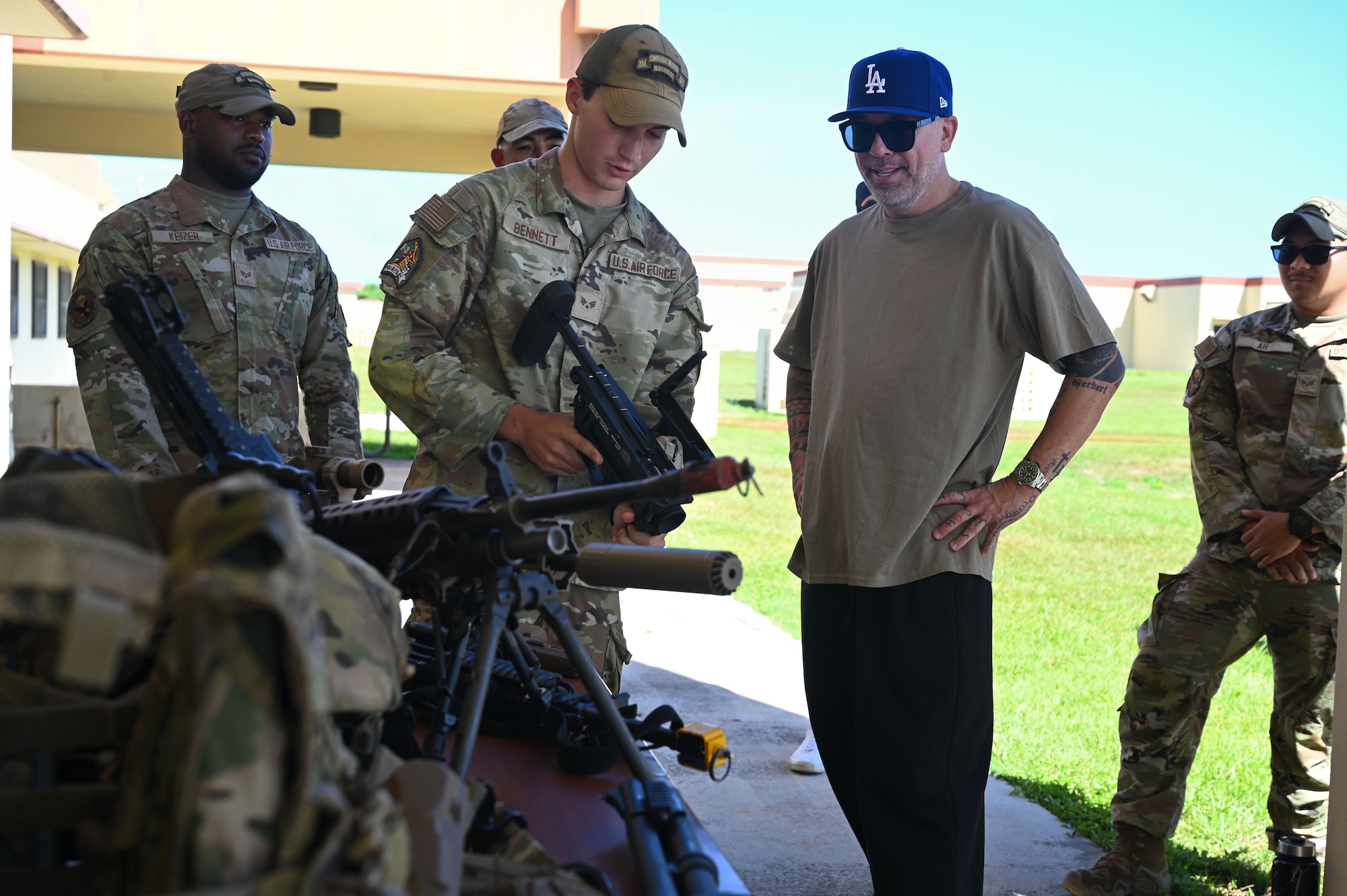 U.S. Air Force Senior Airman Christopher Bennett, 736th Security Forces Squadron, explains the different weapon capabilities to American comedian and actor, Jo Koy, at the Pacific Regional Training Facility- Andersen, Guam, Feb. 1, 2025. Jo Koy visited the island as part of his USO comedy tour performing for military service members stationed in Japan and Guam. (U.S. Air Force photo by Airman 1st Class Natasha Ninete).