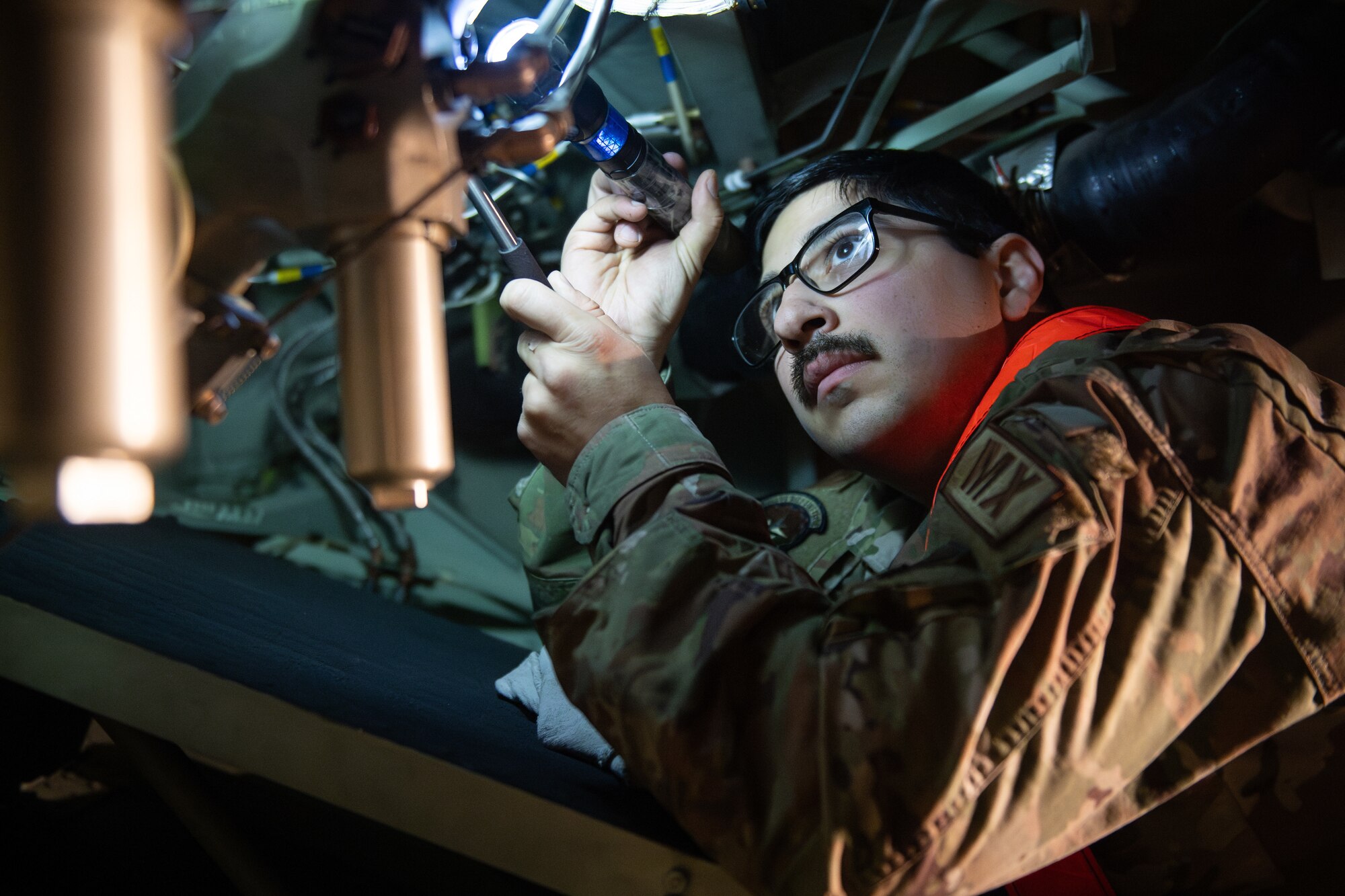An Airman uses a flashlight to inspect aircraft parts.