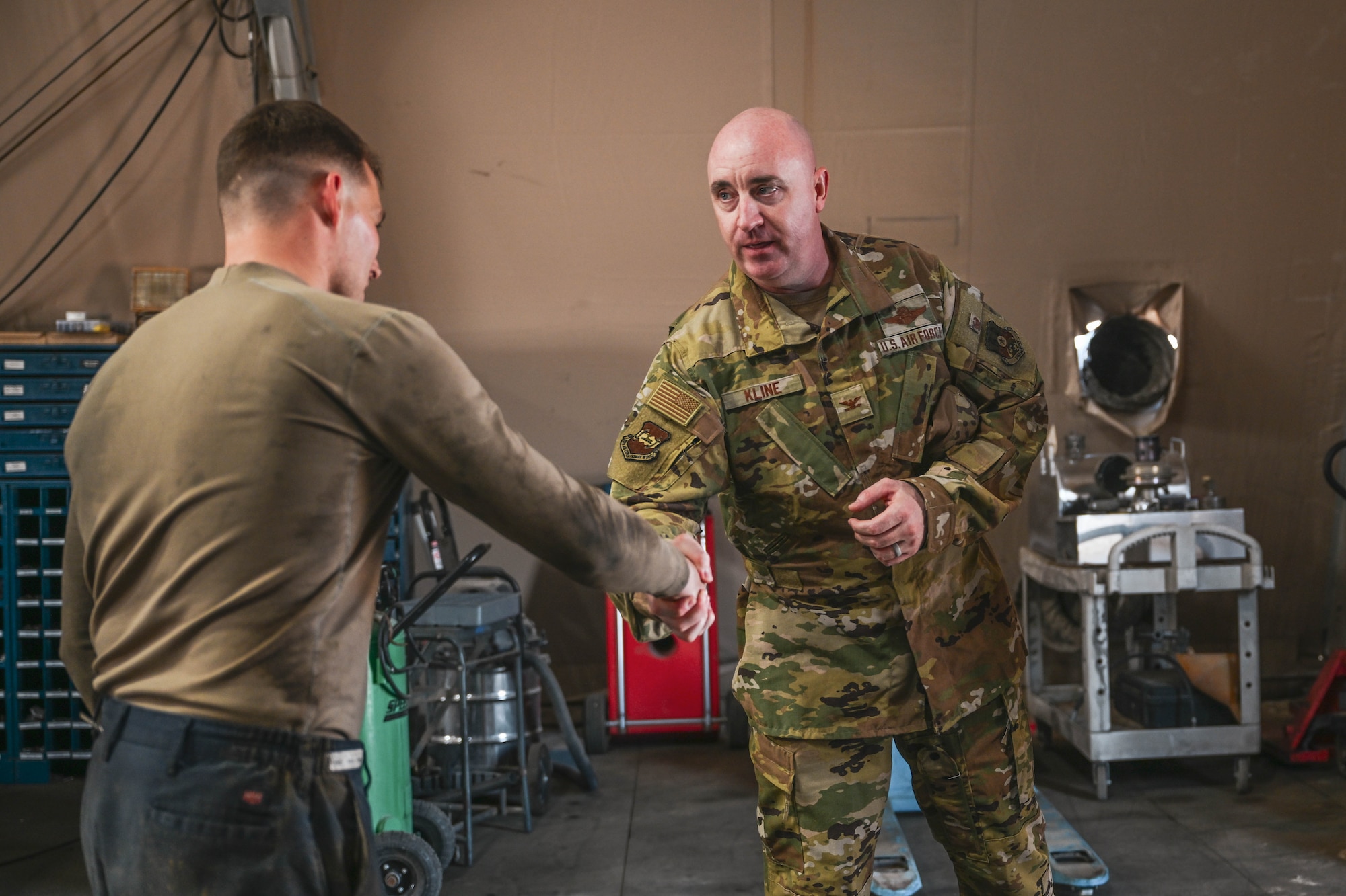 A man in uniform shakes another man's hands.