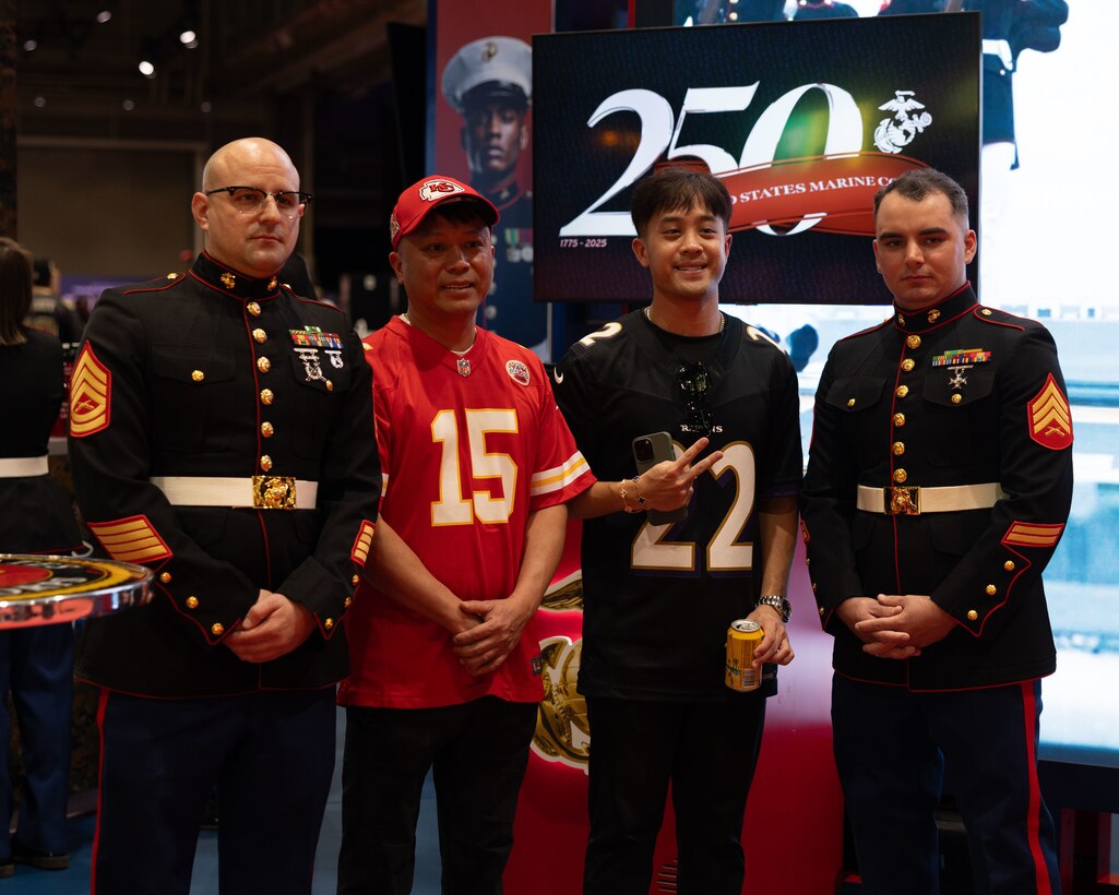U.S. Marine Corps Gunnery Sgt. John Rethage (left) aviation electronics technician, Marine Medium Tiltrotor Squadron (VMM) 774, 4th Marine Airwing, and Sgt. Nicholas Cole, airframes mechanic, Marine Medium Tiltrotor Squadron (VMM) 774, 4th Marine Aircraft Wing, pose for a photo with attendees during the NFL’s Super Bowl Fan Zone Experience at the Ernest N. Morial Convention Center, New Orleans, Feb. 5, 2025. Marines from Marine Medium Tiltrotor Squadron (VMM) 774 and 764 participated in the experience, giving them the opportunity to interact with the American public, increase knowledge about the Marine Corps Reserve and kickoff the celebration of the U.S. Marine Corps’ 250th birthday. (U.S. Marine Corps Photo by Lance Cpl. Juan Diaz)