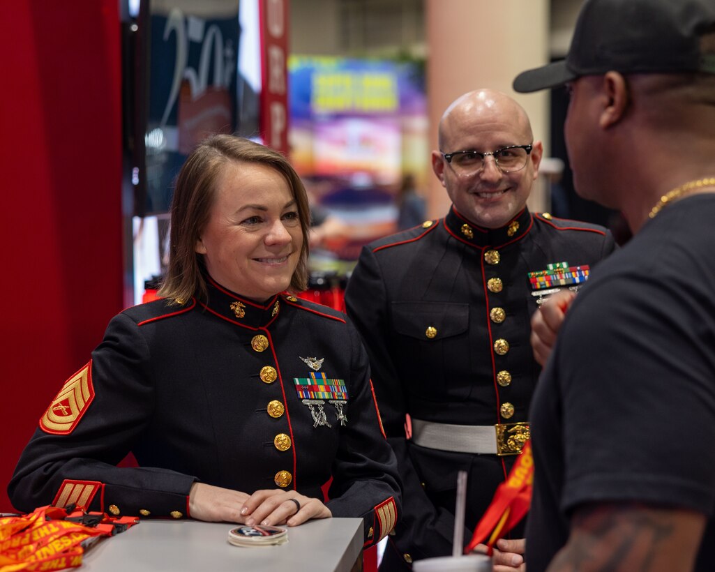 U.S. Marine Corps Gunnery Sgt. Jami Wardfarber, (left), crew chief, Marine Medium Tiltrotor Squadron (VMM) 764, 4th Marine Aircraft Wing, and Gunnery Sgt. John Rethage, aviation electronics technician, Marine Medium Tiltrotor Squadron (VMM) 774, 4th Marine Aircraft Wing, interact with an attendee during the NFL’s Super Bowl Fan Zone Experience at the Ernest N. Morial Convention Center, New Orleans, Feb. 5, 2025. Marines from Marine Medium Tiltrotor Squadron (VMM) 774 and 764 participated in the experience, giving them the opportunity to interact with the American public, increase knowledge about the Marine Corps Reserve and kickoff the celebration of the U.S. Marine Corps’ 250th birthday. (U.S. Marine Corps Photo by Lance Cpl. Juan Diaz)