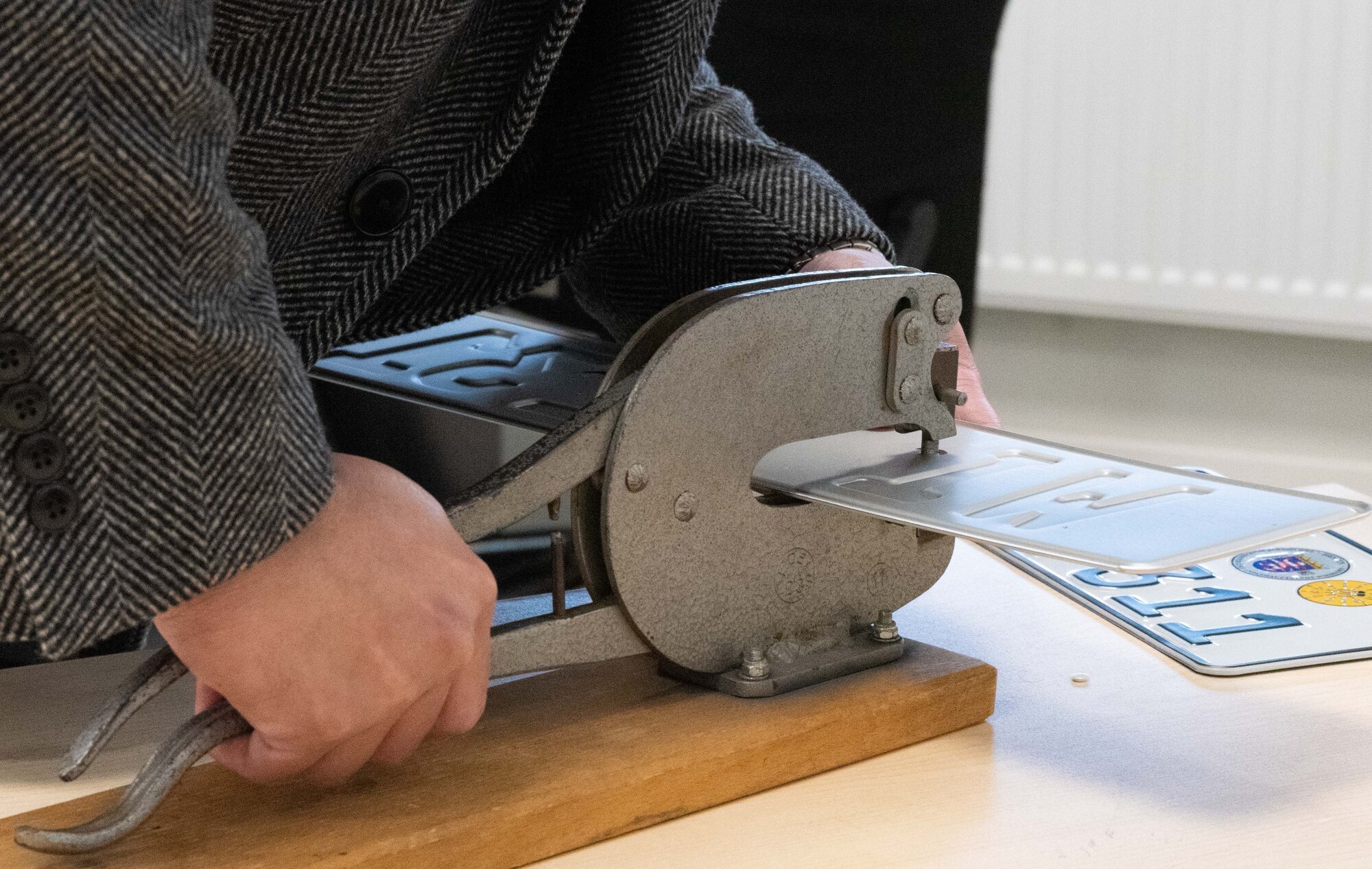 A customer at the Wiesbaden Vehicle Registration Office punches holes in a new license plate. (Photo Credit: Stephen Perez)