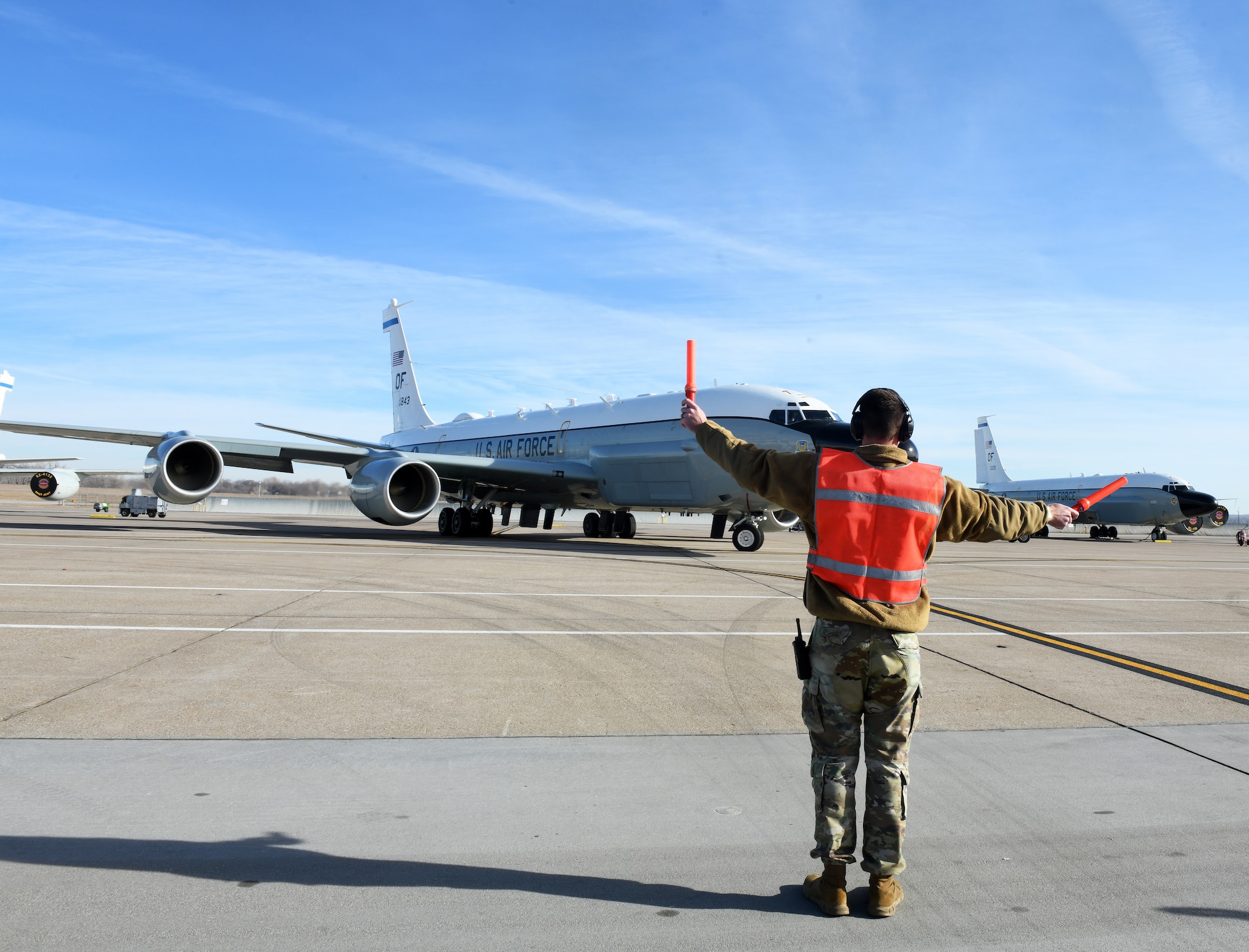 Nebraska Air National Guard's 170th Group member marshals a RC-135 Rivet Joint aircraft before it takes flight.