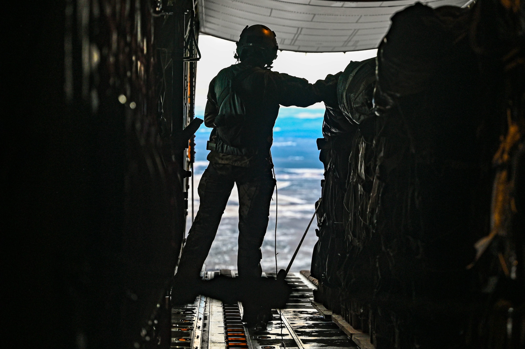 A loadmaster, assigned to the 61st Airlift Squadron, prepares for a container delivery system airdrop during the Joint Pacific Multinational Readiness Center (JPMRC) 25-02 exercise at Joint Base Elmendorf-Richardson, Alaska, Jan. 19, 2025. The C-130 aircraft is capable of operating from rough, dirt strips and is the prime transport for airdropping troops and equipment into hostile areas.