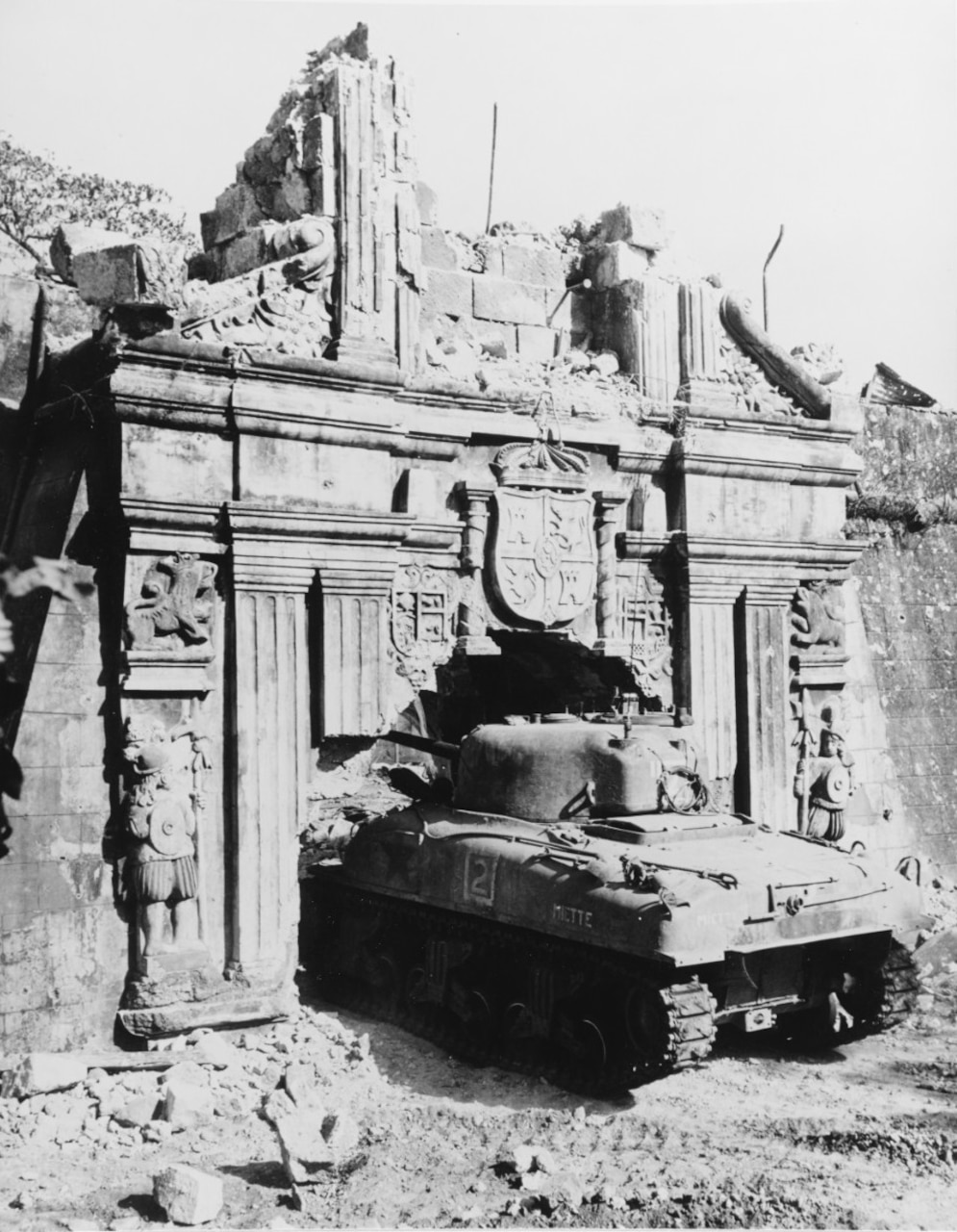A tank sits amongst the rubble of a war-torn building.