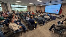 Person delivers presentation in front of a larger group of seated people