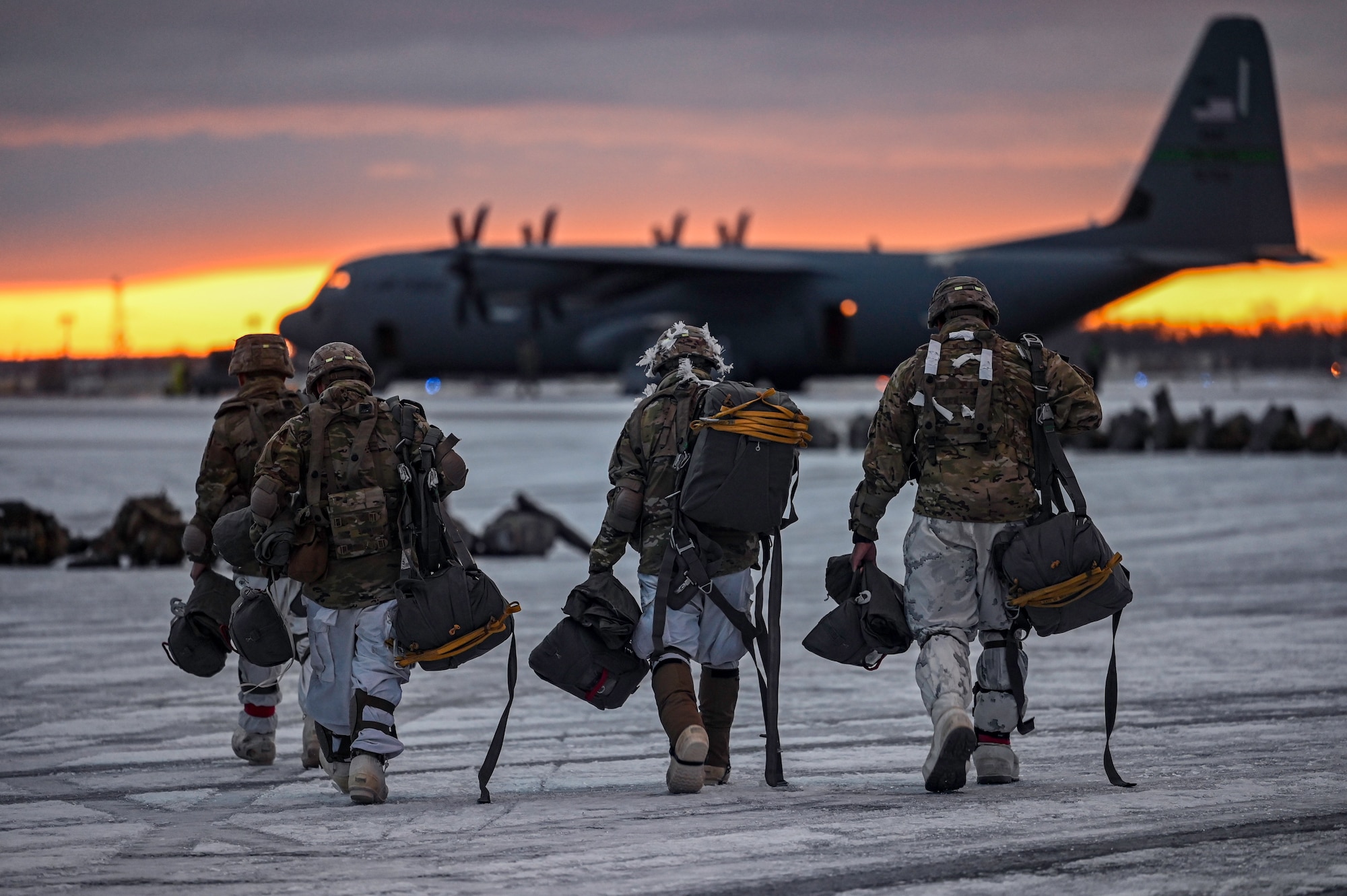 Paratroopers assigned to the 2nd Infantry Brigade Combat Team (Airborne), 11th Airborne Division, walk towards a C-130J Super Hercules aircraft, assigned to the 19th Airlift Wing, prior to a Joint Forcible Entry (JFE) to kick off Joint Pacific Multinational Readiness Center 25-02, at Joint Base Elmendorf-Richardson, Alaska, Jan. 22, 2025. The 19th Airlift Wing operates the largest C-130 fleet in the world, providing unmatched tactical airlift capabilities.