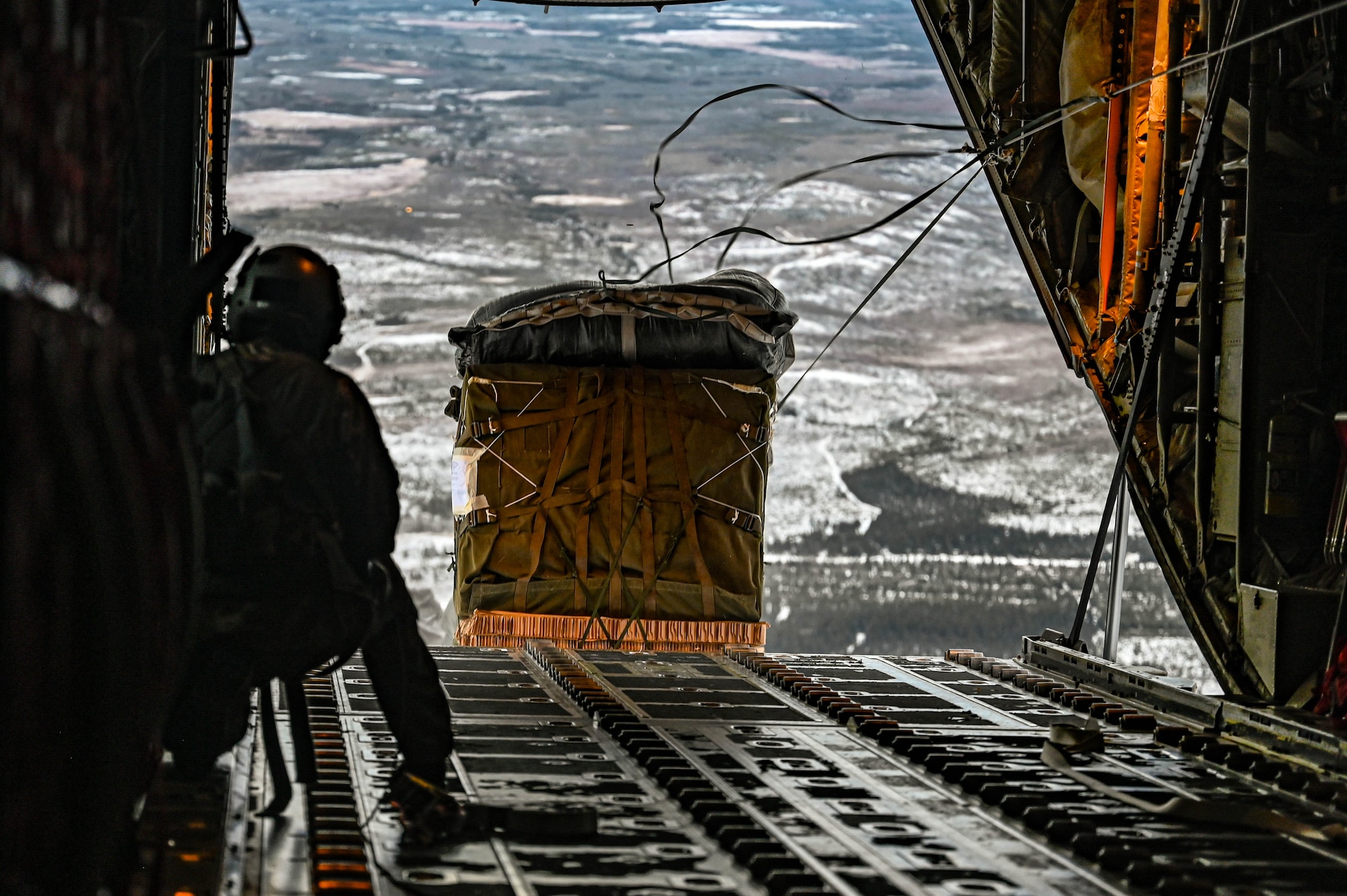 A loadmaster, assigned to the 61st Airlift Squadron, watches a container delivery system exit a C-130J Super Hercules aircraft during the Joint Pacific Multinational Readiness Center (JPMRC) 25-02 exercise at Joint Base Elmendorf-Richardson, Alaska, Jan. 19, 2025. The 19th Airlift Wing’s successful airdrop validated strategic infiltration capabilities, enabling the rapid insertion of a HIMARS unit and demonstrating the Joint Force’s capability to swiftly project combat power.