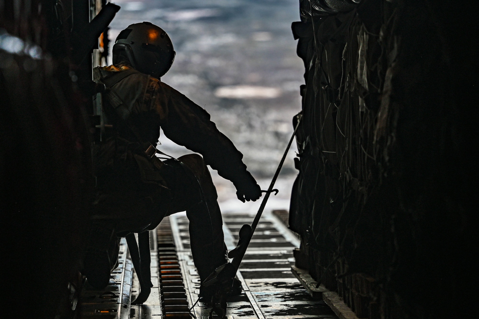 A loadmaster, assigned to the 61st Airlift Squadron, prepares to cut a release gate for a container delivery system airdrop during the Joint Pacific Multinational Readiness Center (JPMRC) 25-02 exercise at Joint Base Elmendorf-Richardson, Alaska, Jan. 19, 2025. The C-130 aircraft is capable of operating from rough, dirt strips and is the prime transport for airdropping troops and equipment into hostile areas.