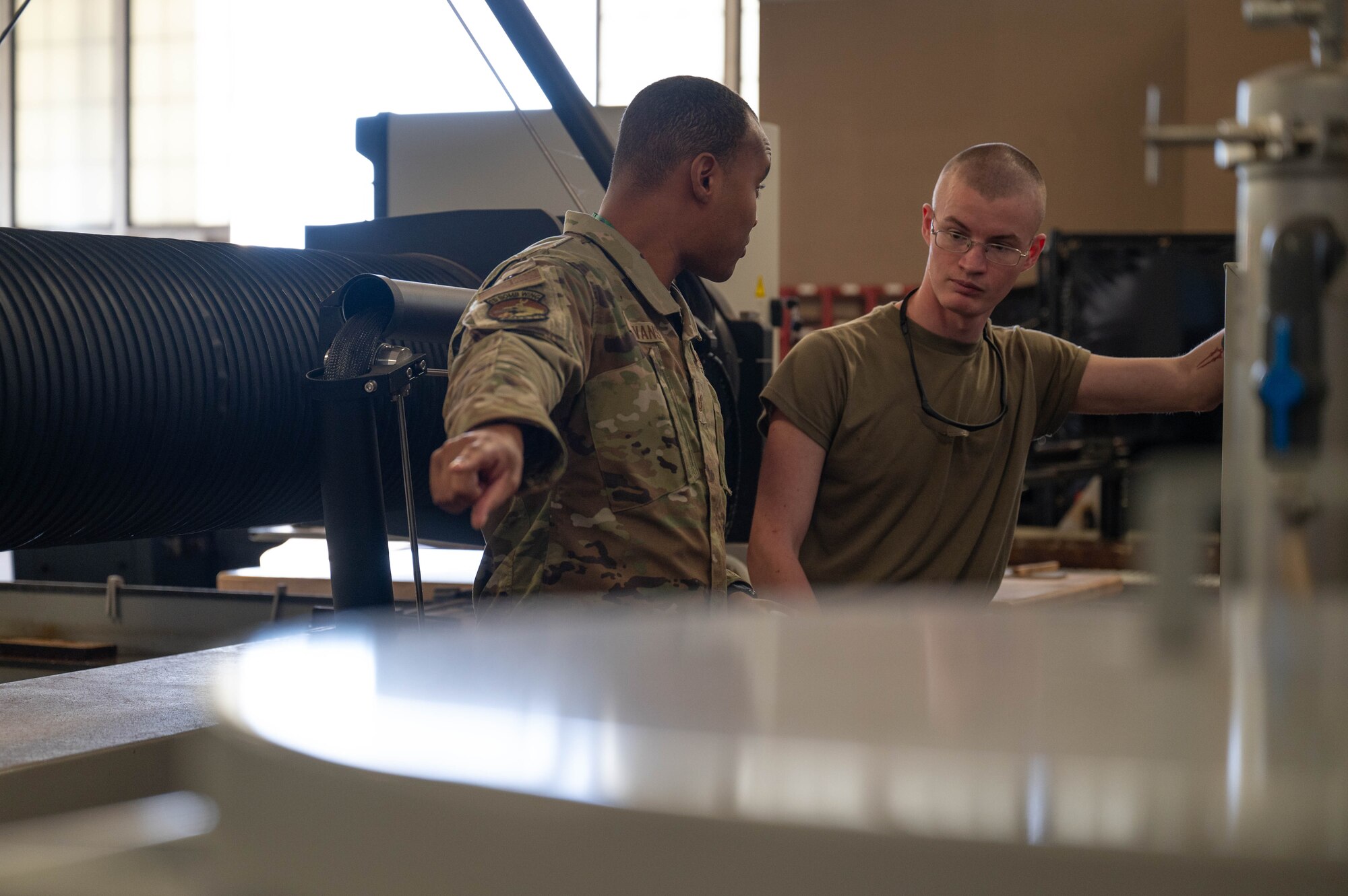 U.S. Air Force Tech. Sgt. Donovan Evans, 2nd Bomb Wing Safety installation safety noncommissioned officer in charge, walks through the aircraft metals technology shop with Airman 1st Class Chistopher Brewer, 2nd Maintenance Squadron aircraft metals technology journeyman at Barksdale Air Force Base, La., Dec. 9, 2024.