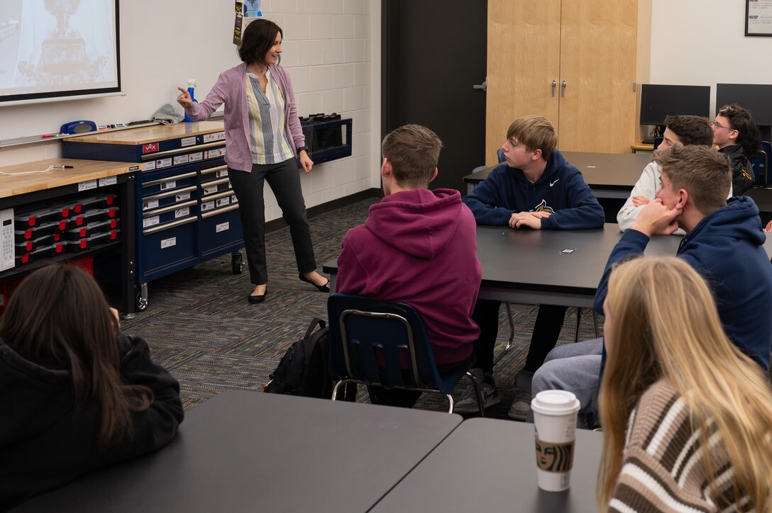 An individual standing in front of a high school class giving a presentatoin.