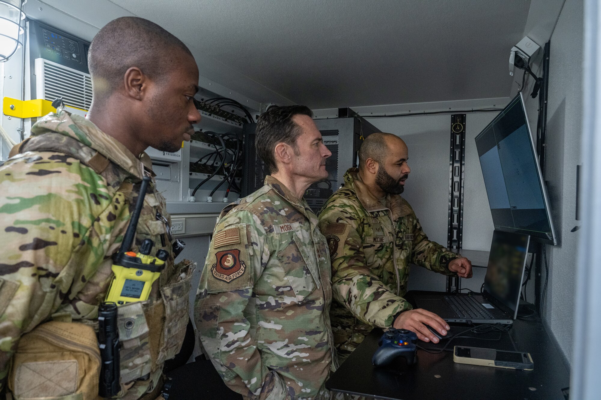 U.S. Air Force Maj. Gen. Paul Moga, center, Third Air Force commander, receives a brief from Senior Airman Chad McCane, right, 100th Security Forces Squadron counter-small unmanned aerial systems program manager, and Senior Airman Danny Walker, 100th SFS response force member, at RAF Mildenhall, England, Jan. 28, 2025. Moga learned about the C-sUAS program and how Team Mildenhall is preventing future drone incursions. (U.S. Air Force photo by Senior Airman Christopher Campbell)