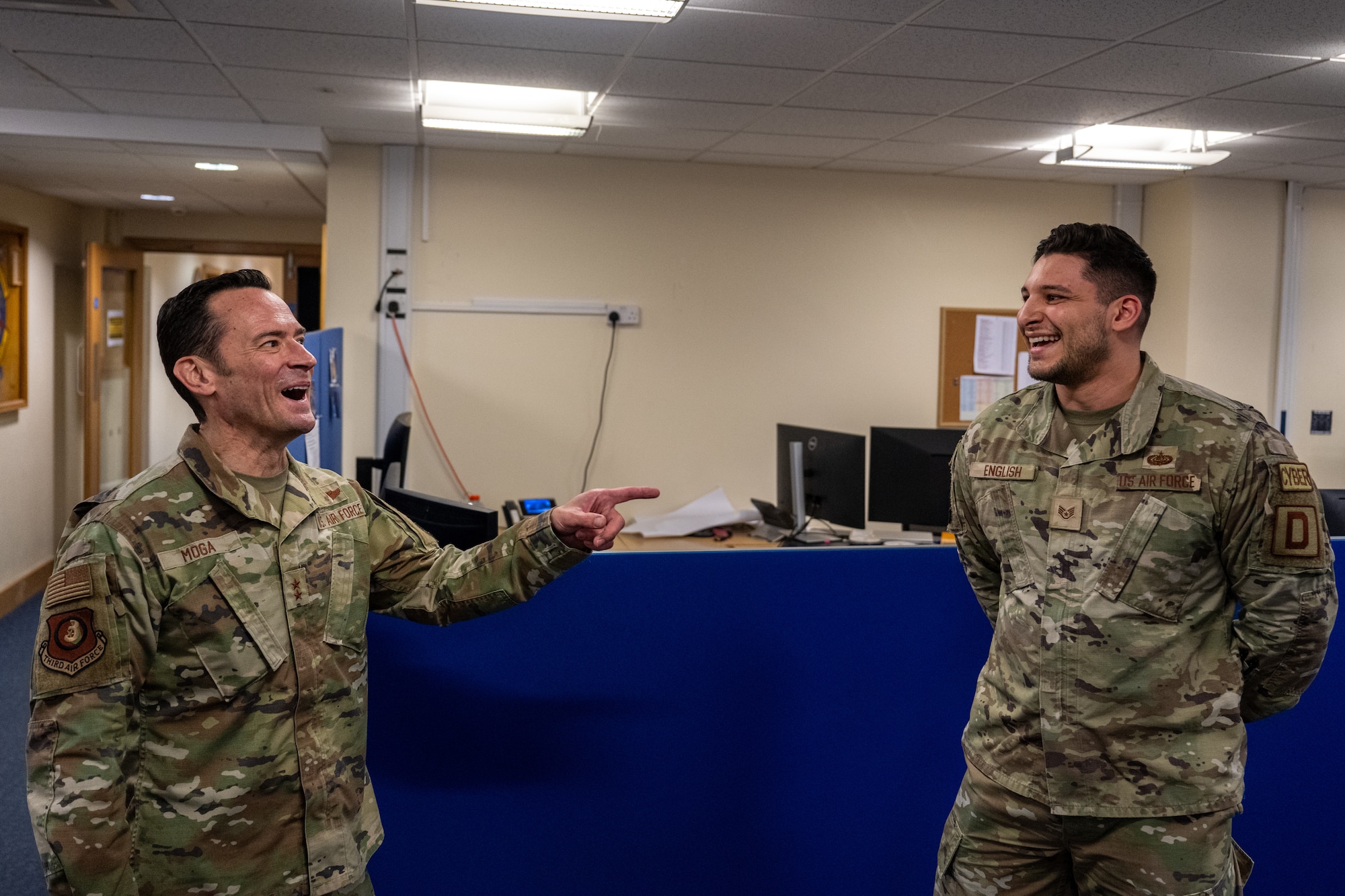 U.S. Air Force Maj. Gen. Paul Moga, left, Third Air Force commander, and Staff Sgt. Henry English, 100th Communications Squadron cybersecurity supervisor, laugh together at RAF Mildenhall, England, Jan. 28, 2025. Moga visited to learn about the 100th Air Refueling Wing’s daily operations, and recognized outstanding Airmen around the installation for their contribution to the mission. (U.S. Air Force photo by Senior Airman Christopher Campbell)