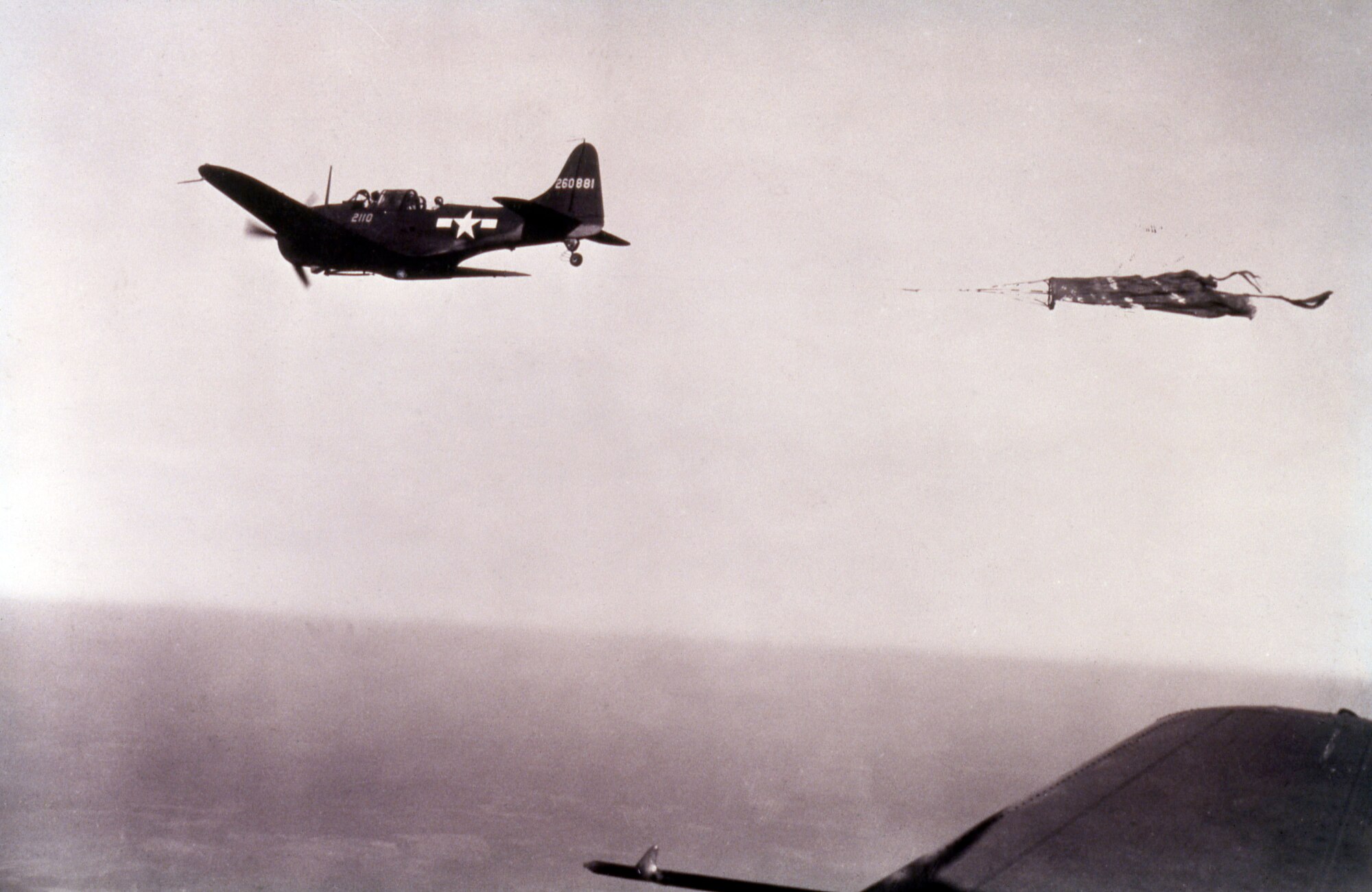 WASP Elsie Dyer piloting a Douglas A-24 Dauntless pulling a target sleeve for tow-target practice by ground-based antiaircraft artillery troops at Camp Davis, NC.