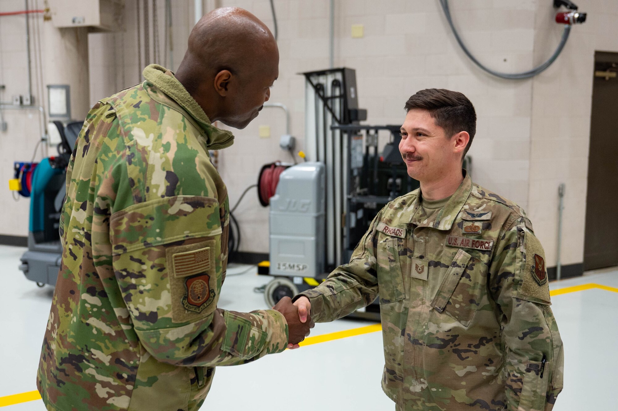 A man in uniform shakes hands with another man in uniform.
