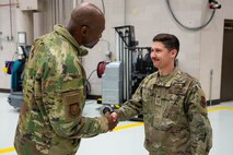 A man in uniform shakes hands with another man in uniform.