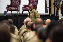 A man in uniform speaks to a crowd of uniformed personnel.