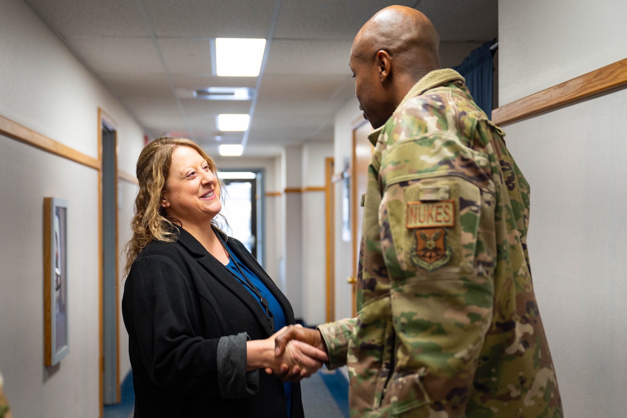 A man in uniform shakes hands with a woman.