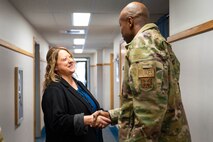 A man in uniform shakes hands with a woman.
