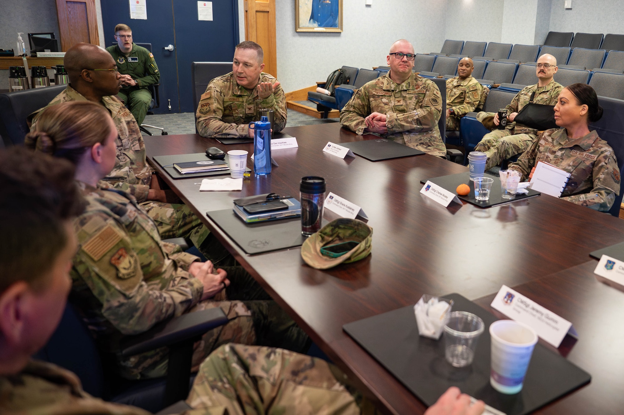 A group of uniformed personnel sit around a table having a discussion.