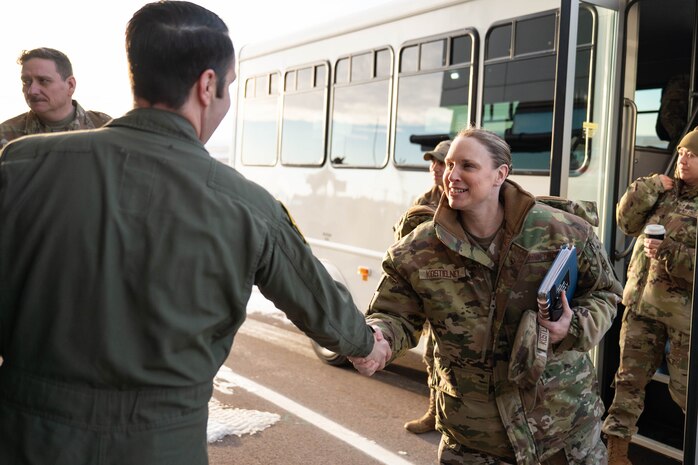 A woman in uniform shakes hands with a man in uniform.