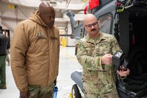 A man in uniform explains something to another man in uniform.