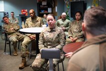 A group of uniformed personnel sit in a meeting.